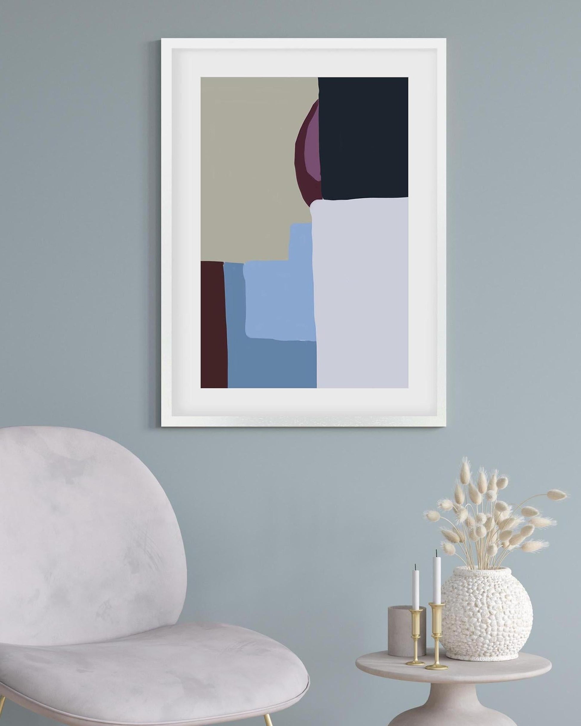 Abstract art print in a white frame on a light blue wall with a modern chair and decorative items.
