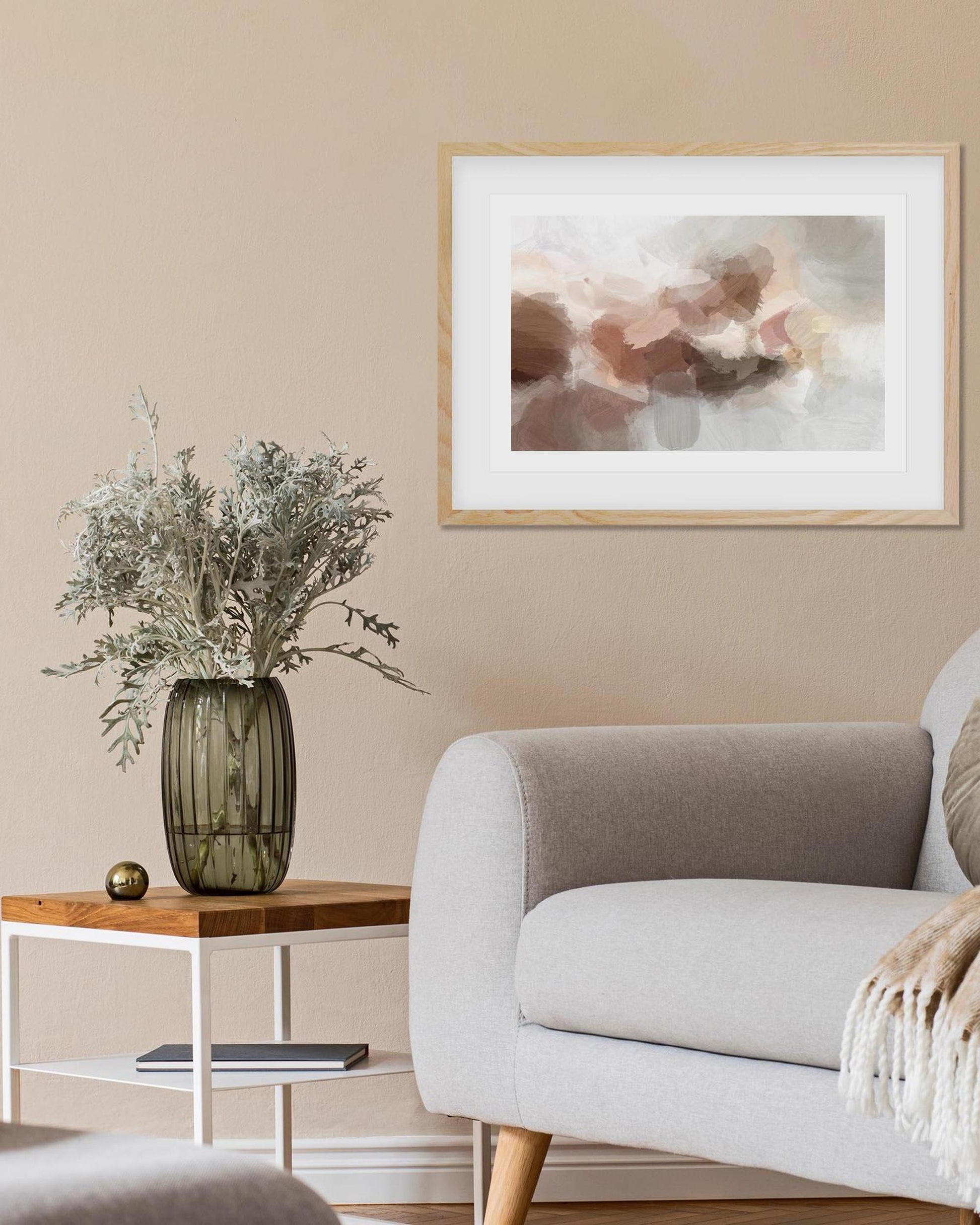 Living room with a gray sofa, wooden side table with a vase, and abstract art on the wall.
