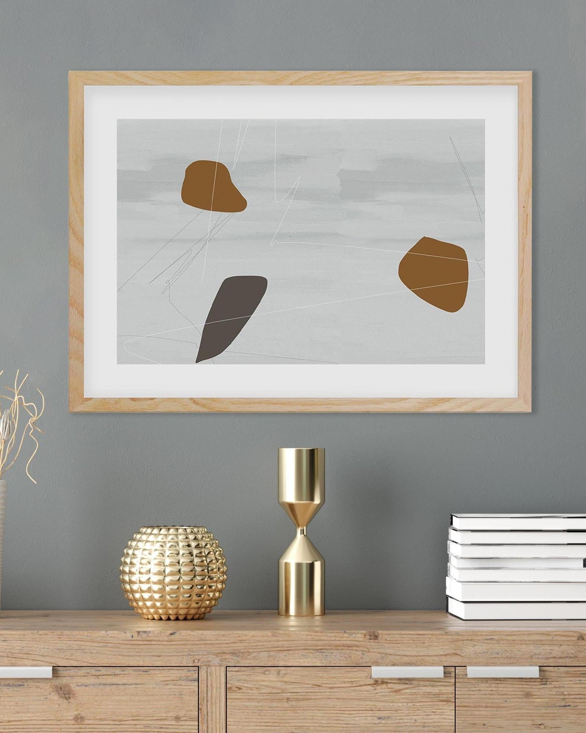 Framed abstract art on a gray wall with decorative items on a wooden surface.