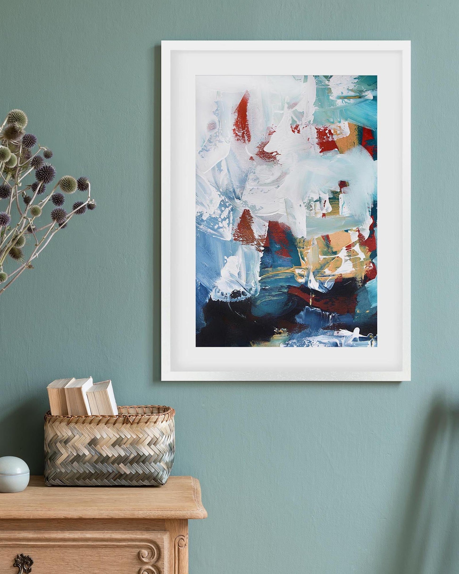 Framed abstract art on a wall with a wooden cabinet and basket below.