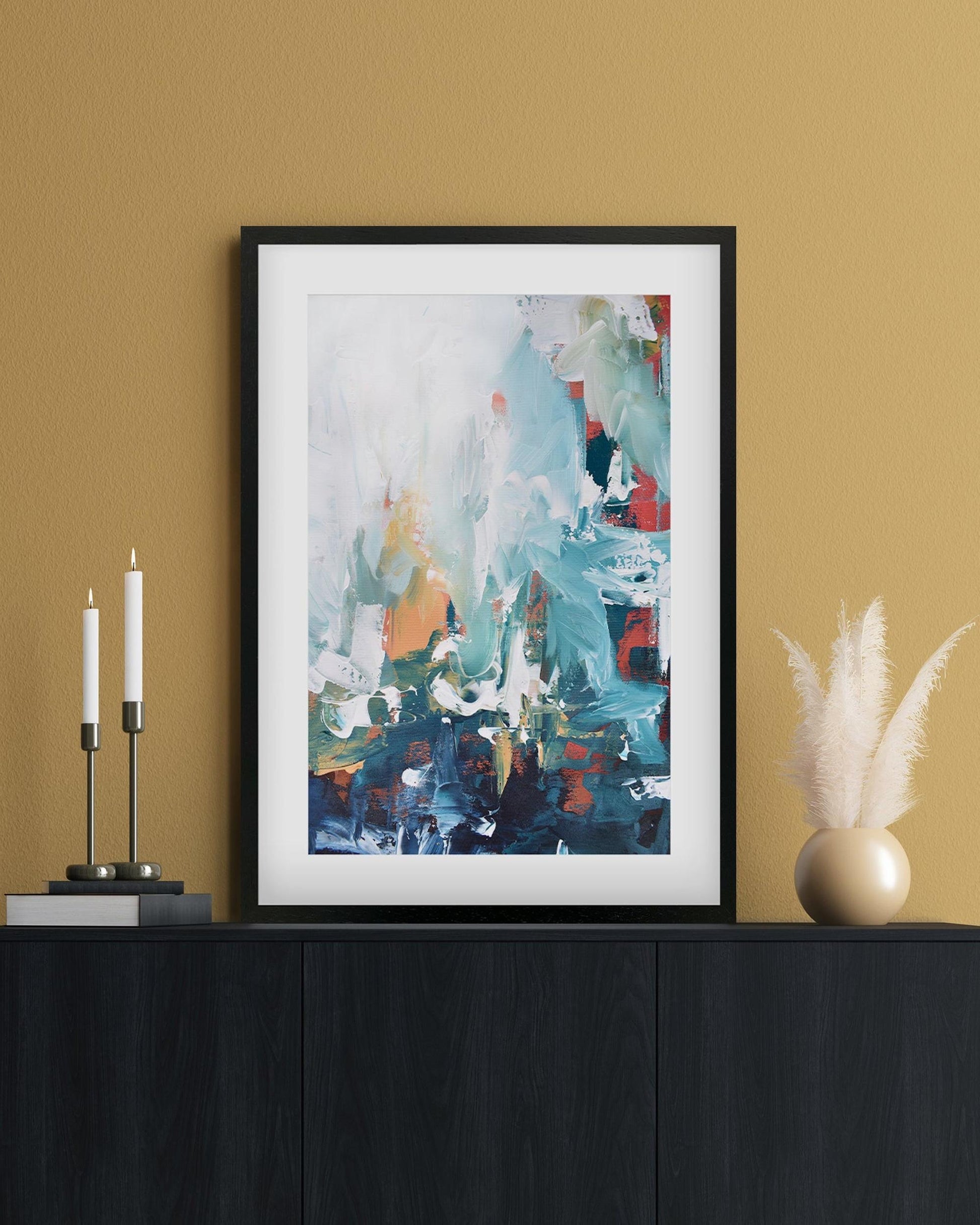 framed abstract artwork on a sideboard by a yellow wall