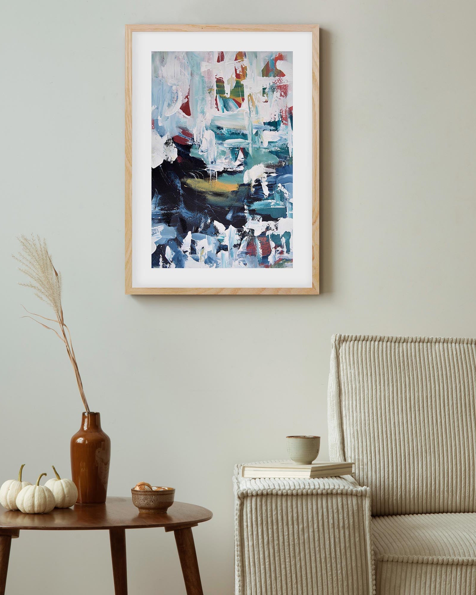 Abstract painting in a wooden frame on a wall above a table with decorative items.
