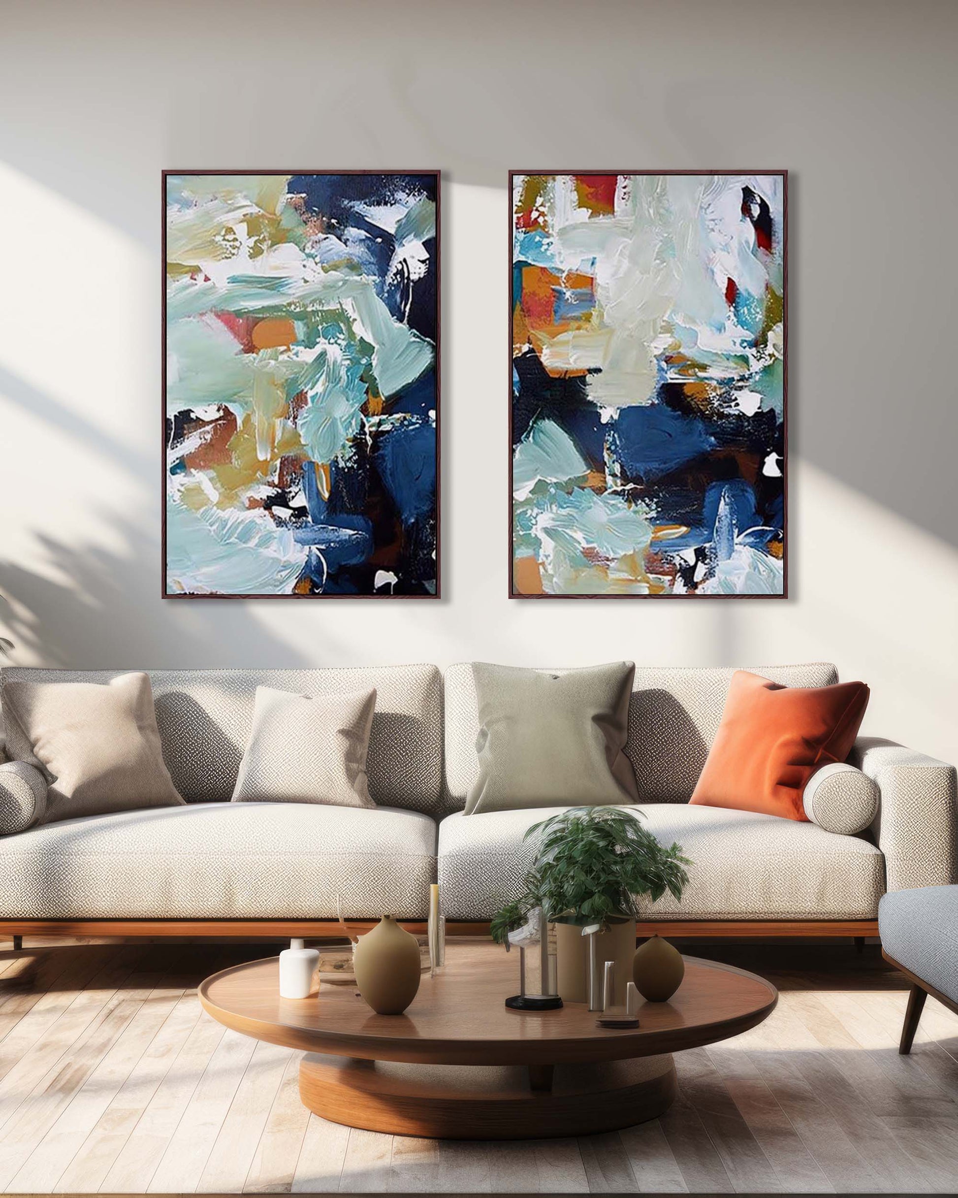 Two abstract paintings on a wall above a sofa in a living room.