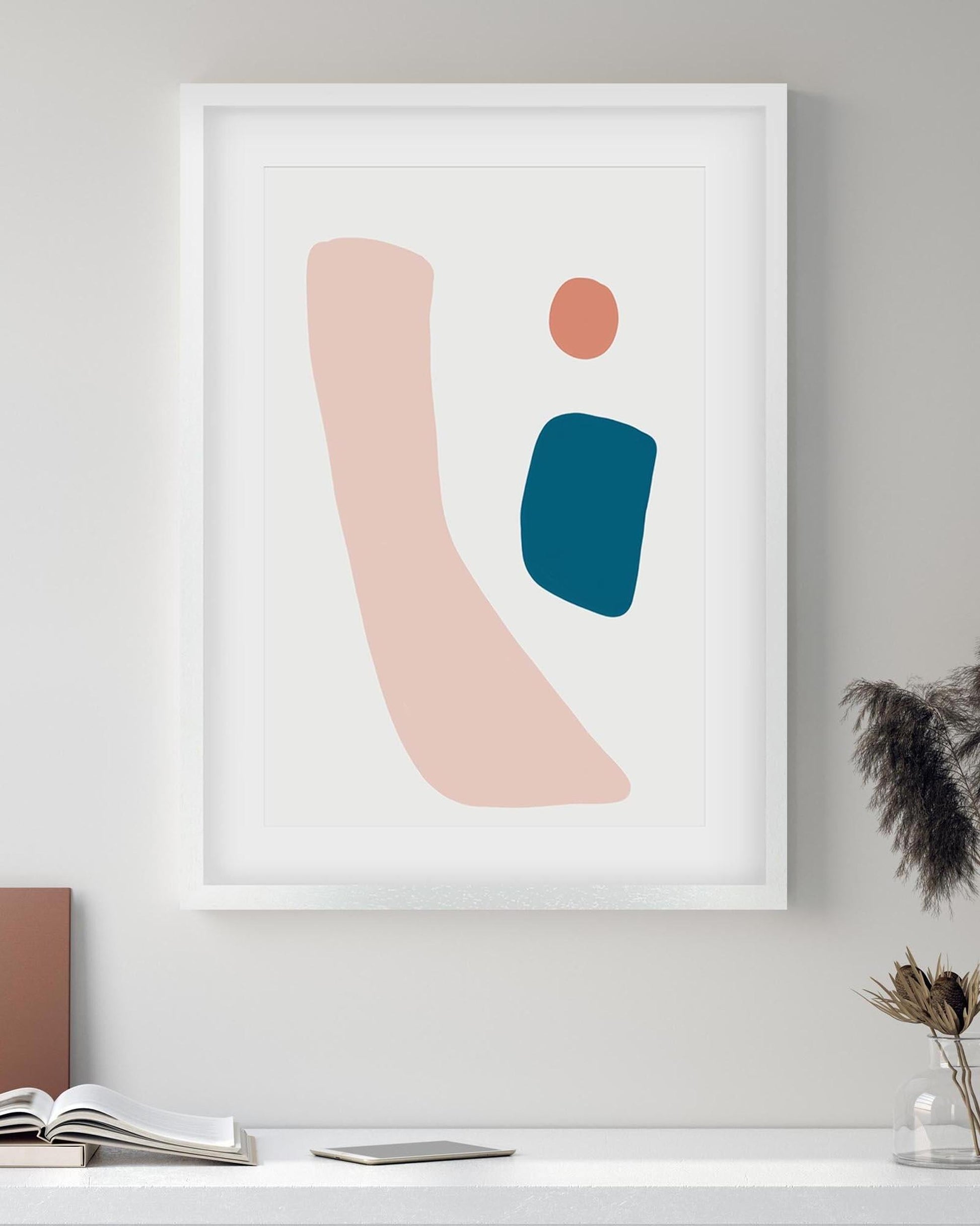 Abstract art print with geometric shapes in pink, blue, and orange on a white wall.