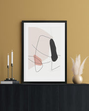 Abstract art print in a black frame on a mustard yellow wall with decorative items.