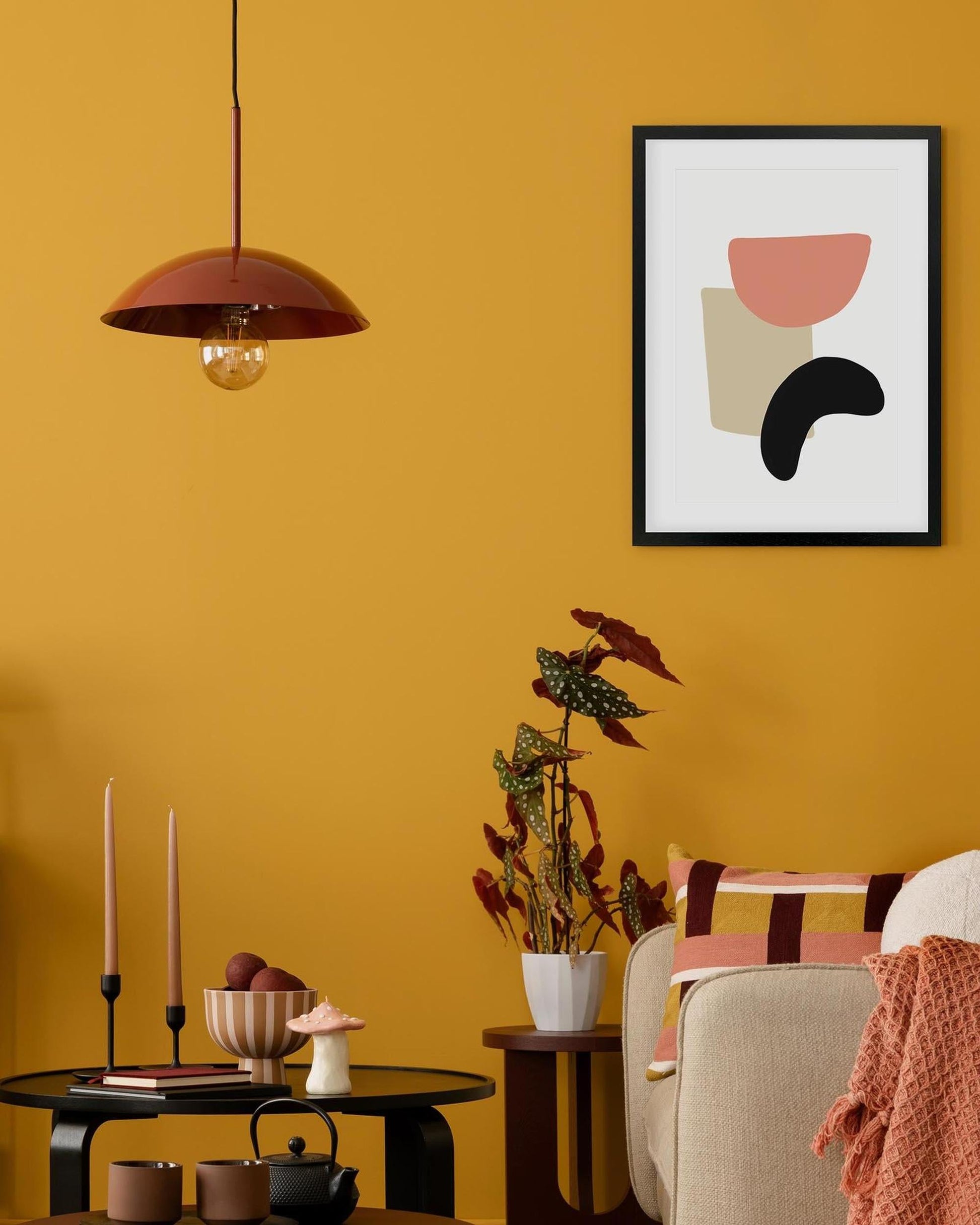 Living room with mustard yellow walls, a framed abstract art piece, and decorative items.