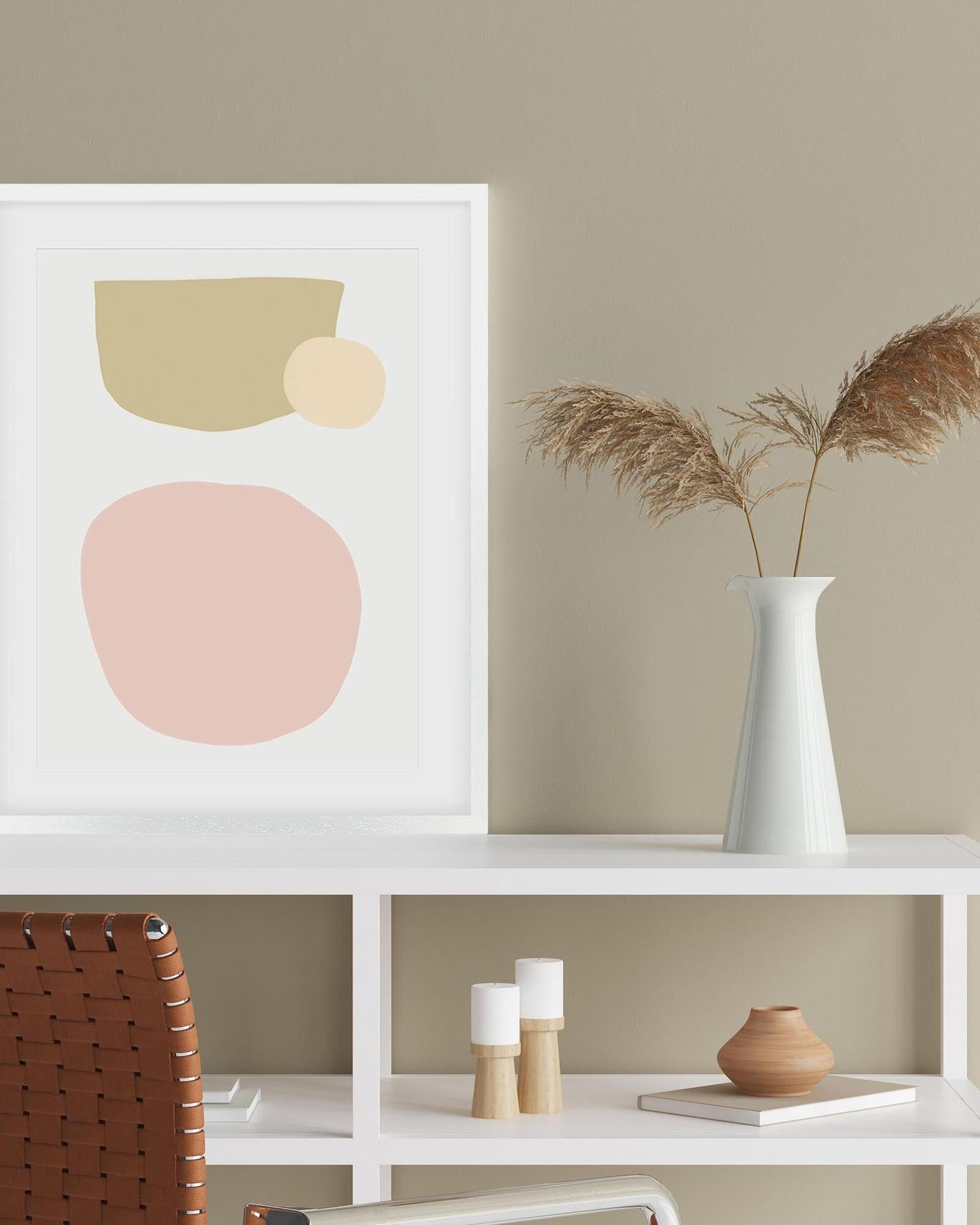 Abstract art print with geometric shapes on a wall above a shelf with decorative items.