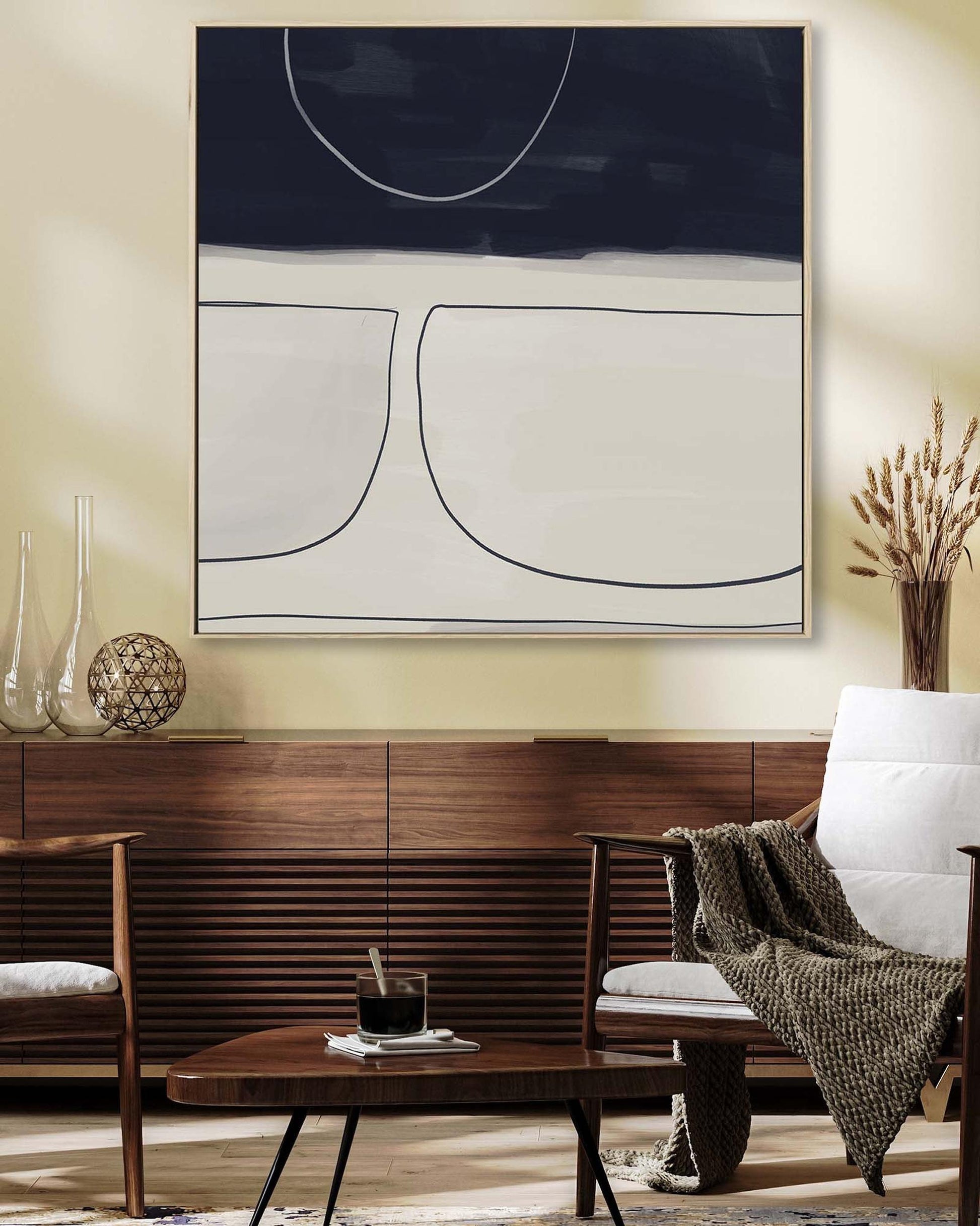 Modern living room with abstract art, wooden furniture, and a white armchair.