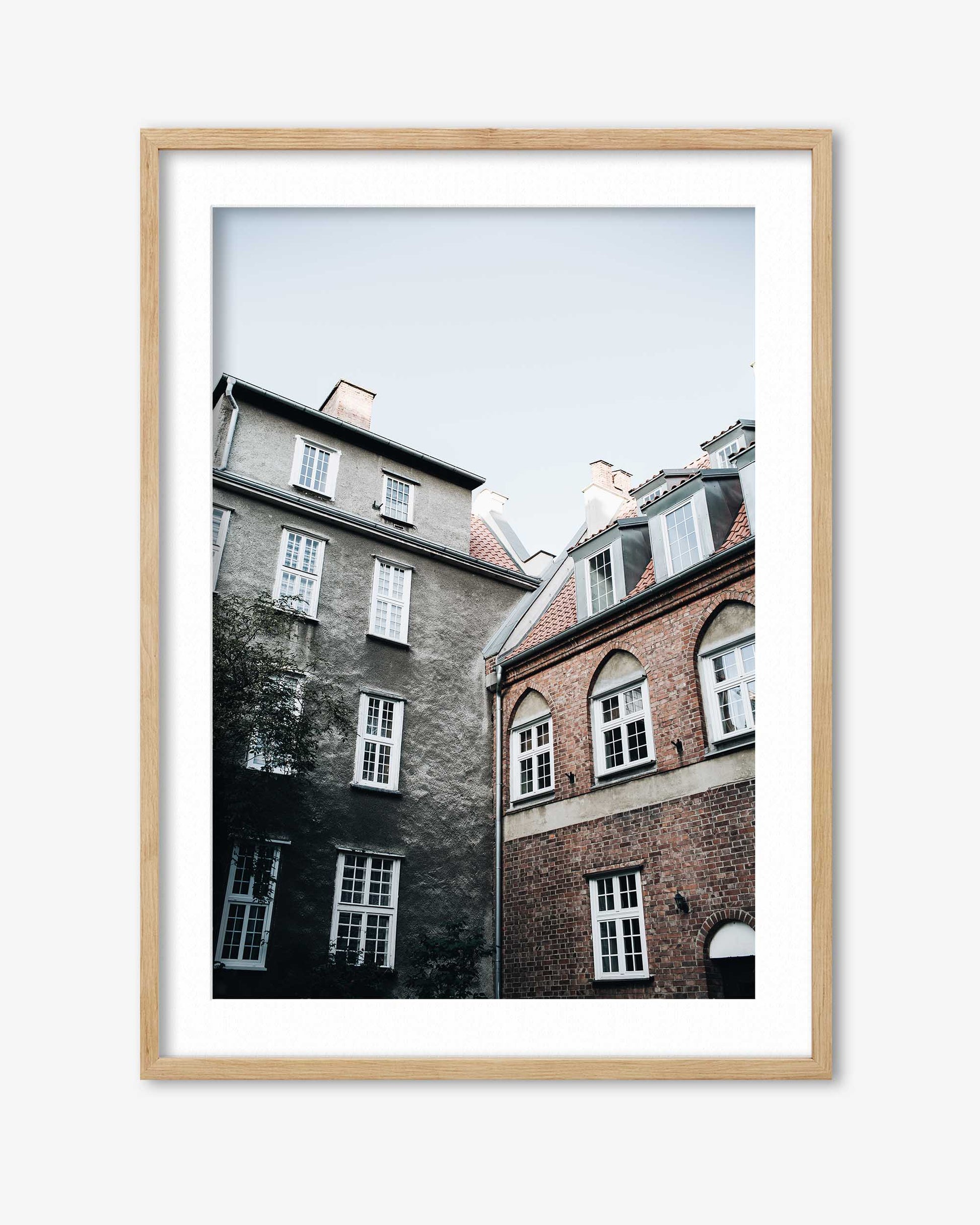 Framed photograph of two buildings with a light wooden frame on a white background