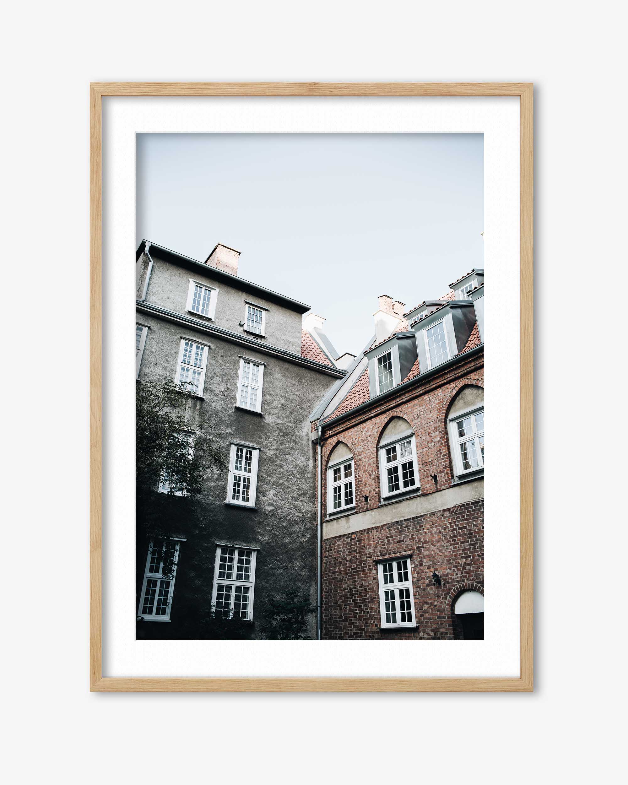 Framed photograph of two buildings with a light wooden frame on a white background