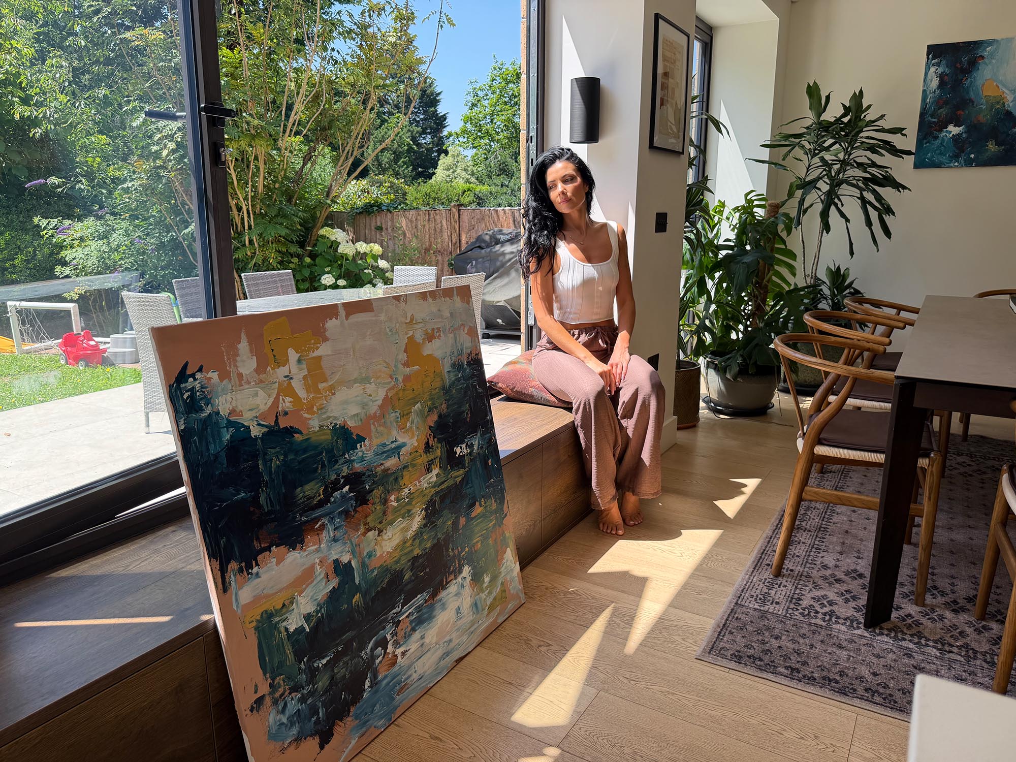Woman sitting on a windowsill with a painting in a sunlit room