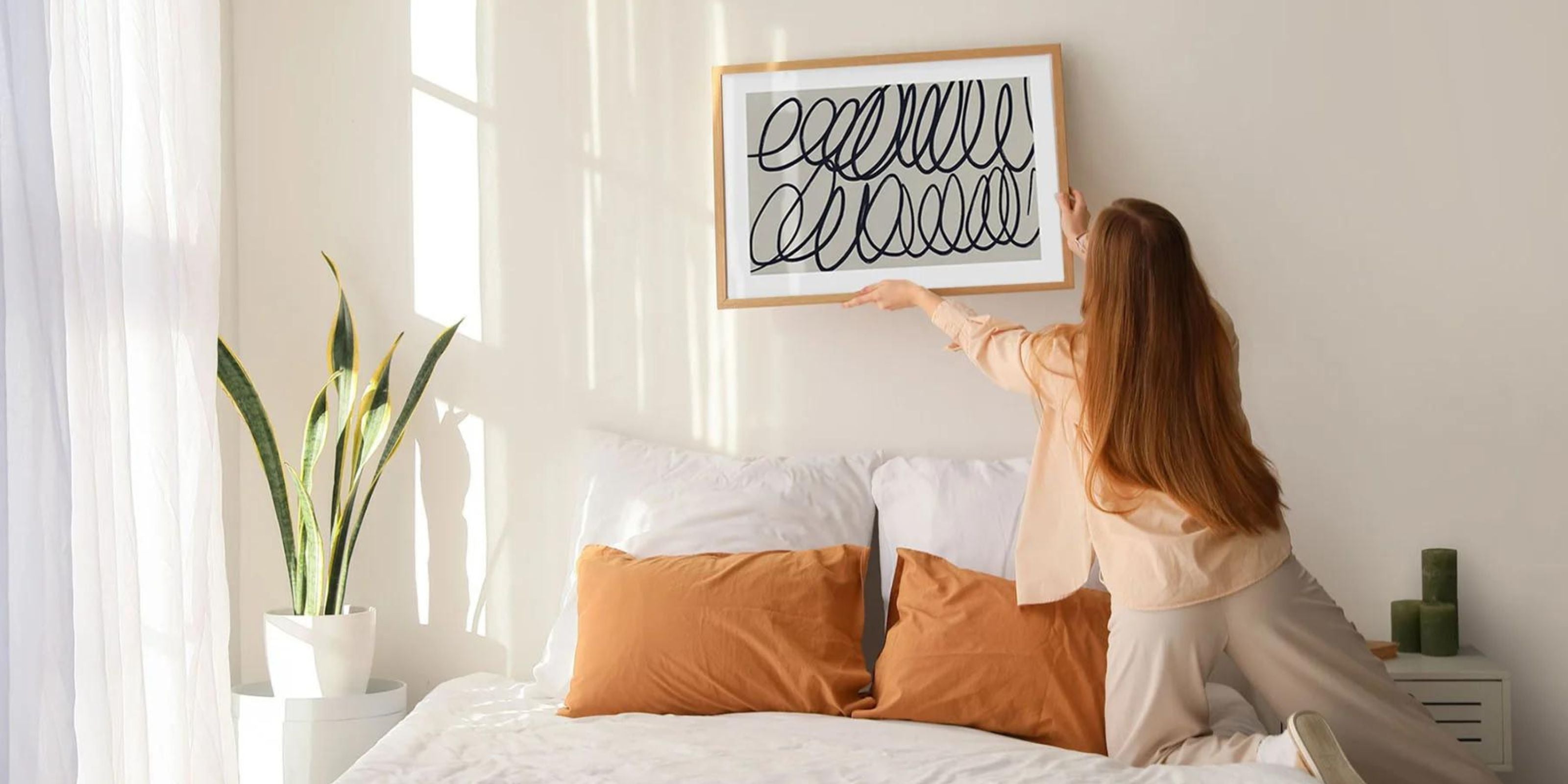 interior designer hanging artwork above bed