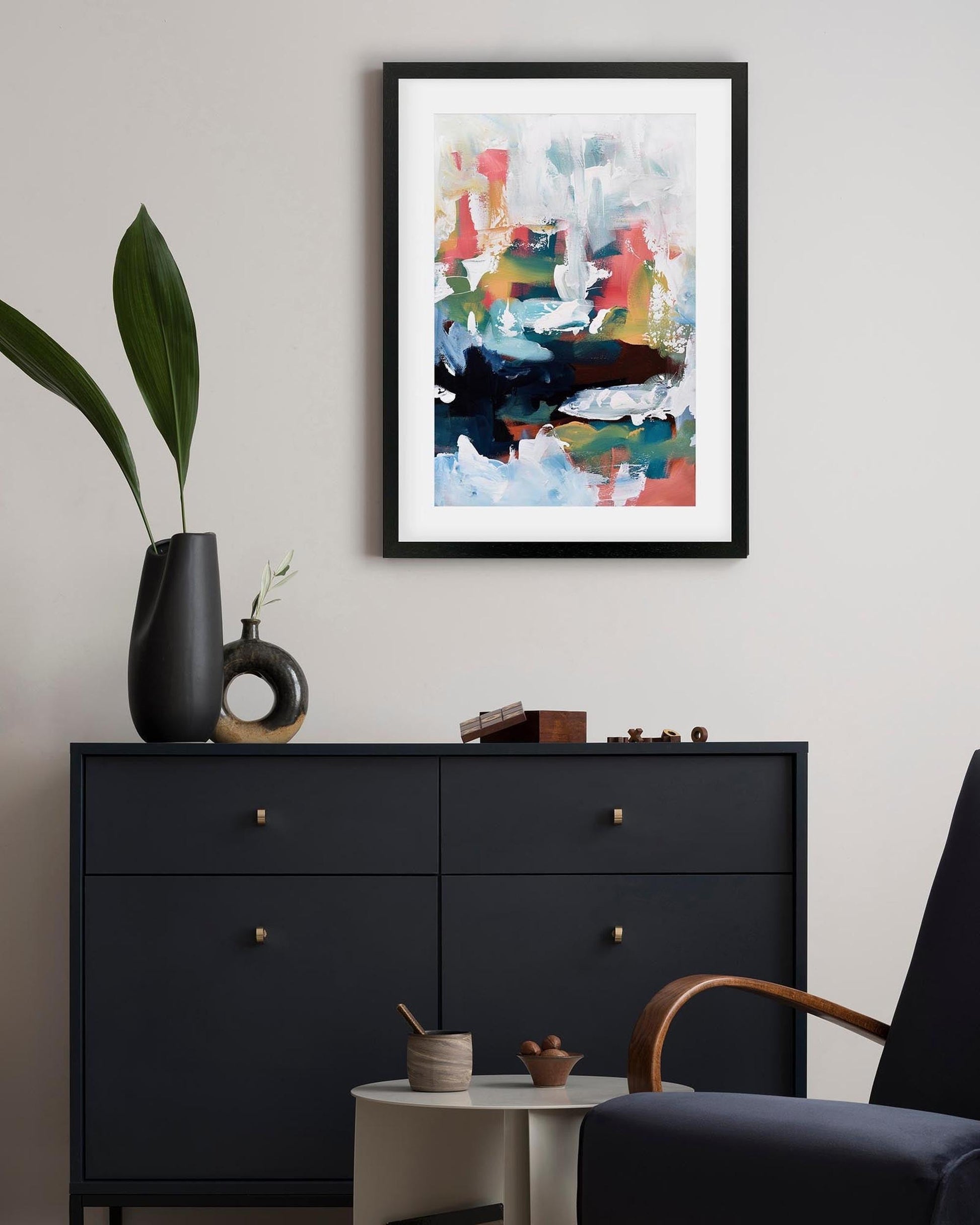 Modern interior with a black dresser, abstract art, and decorative items.