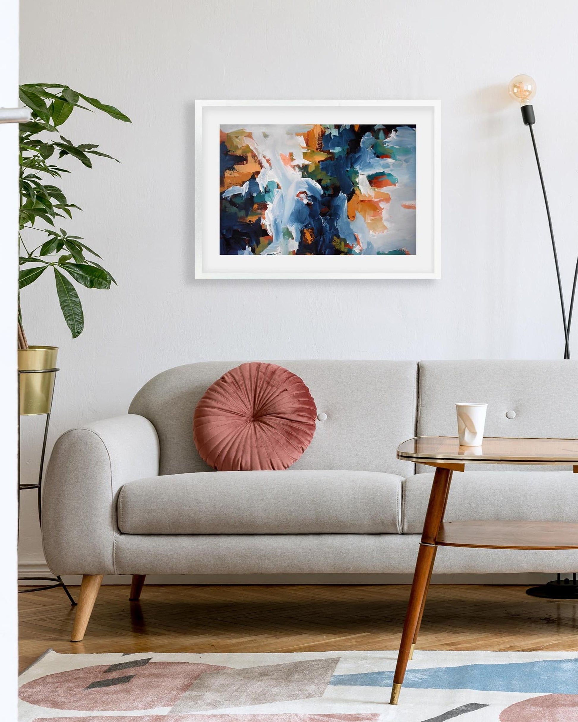 Modern living room with a gray sofa, wooden coffee table, and abstract art on the wall.