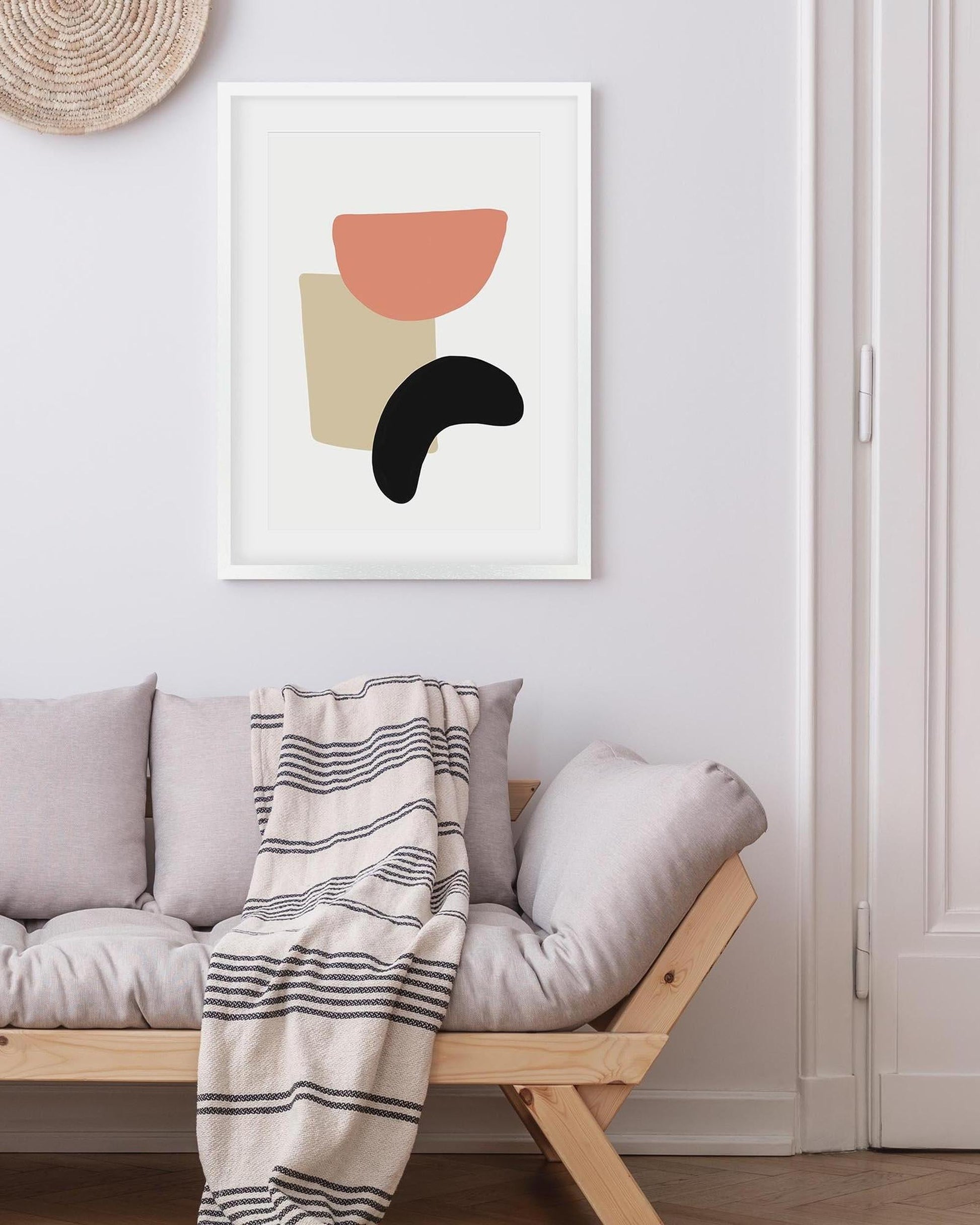 Abstract art print on a wall above a sofa with a striped blanket
