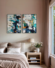 Two abstract paintings above a bed in a bedroom with a lamp and books on a nightstand.