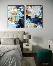Two abstract paintings on a wall above a bed in a bedroom setting.