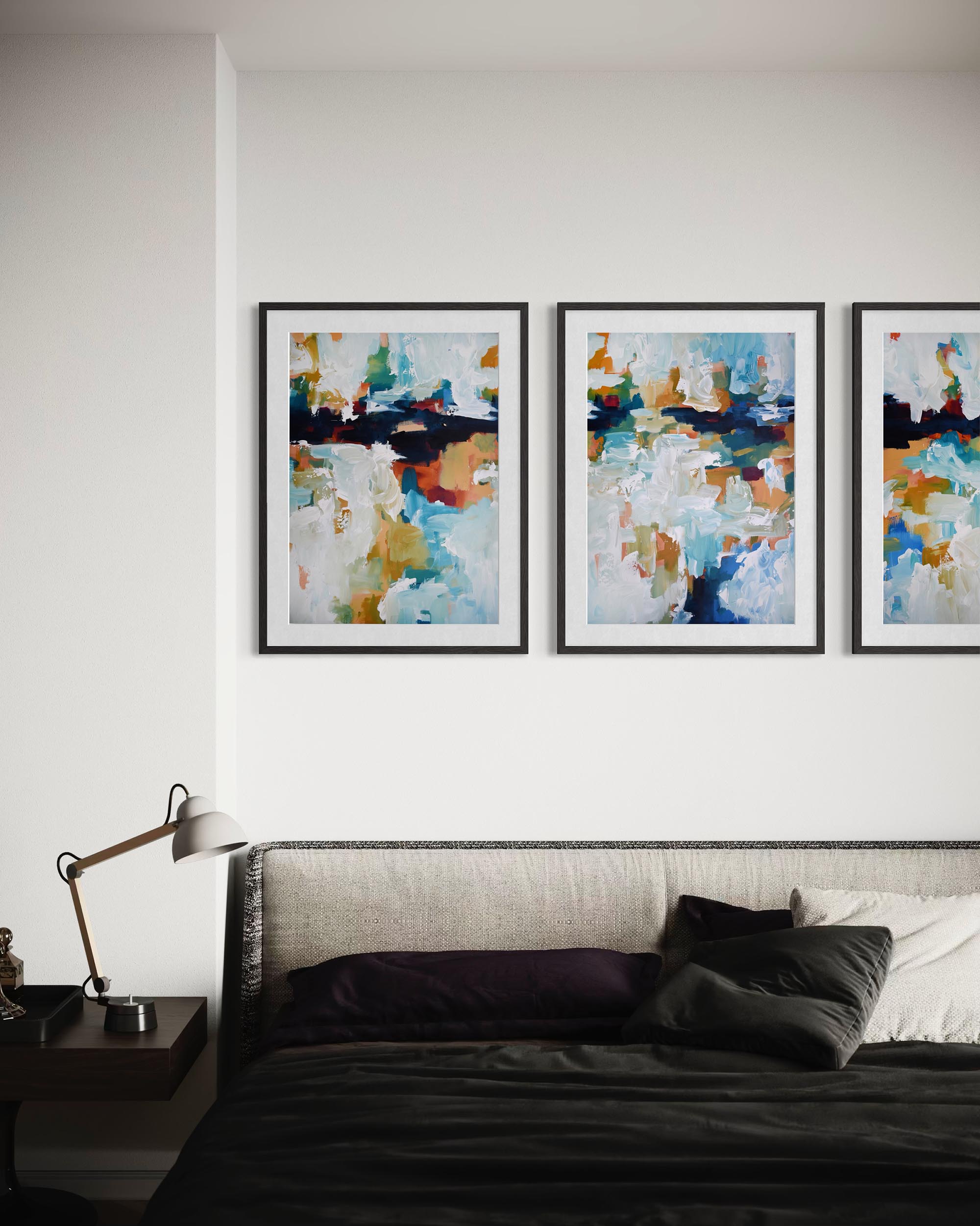Three abstract paintings on a wall above a bed in a bedroom setting.