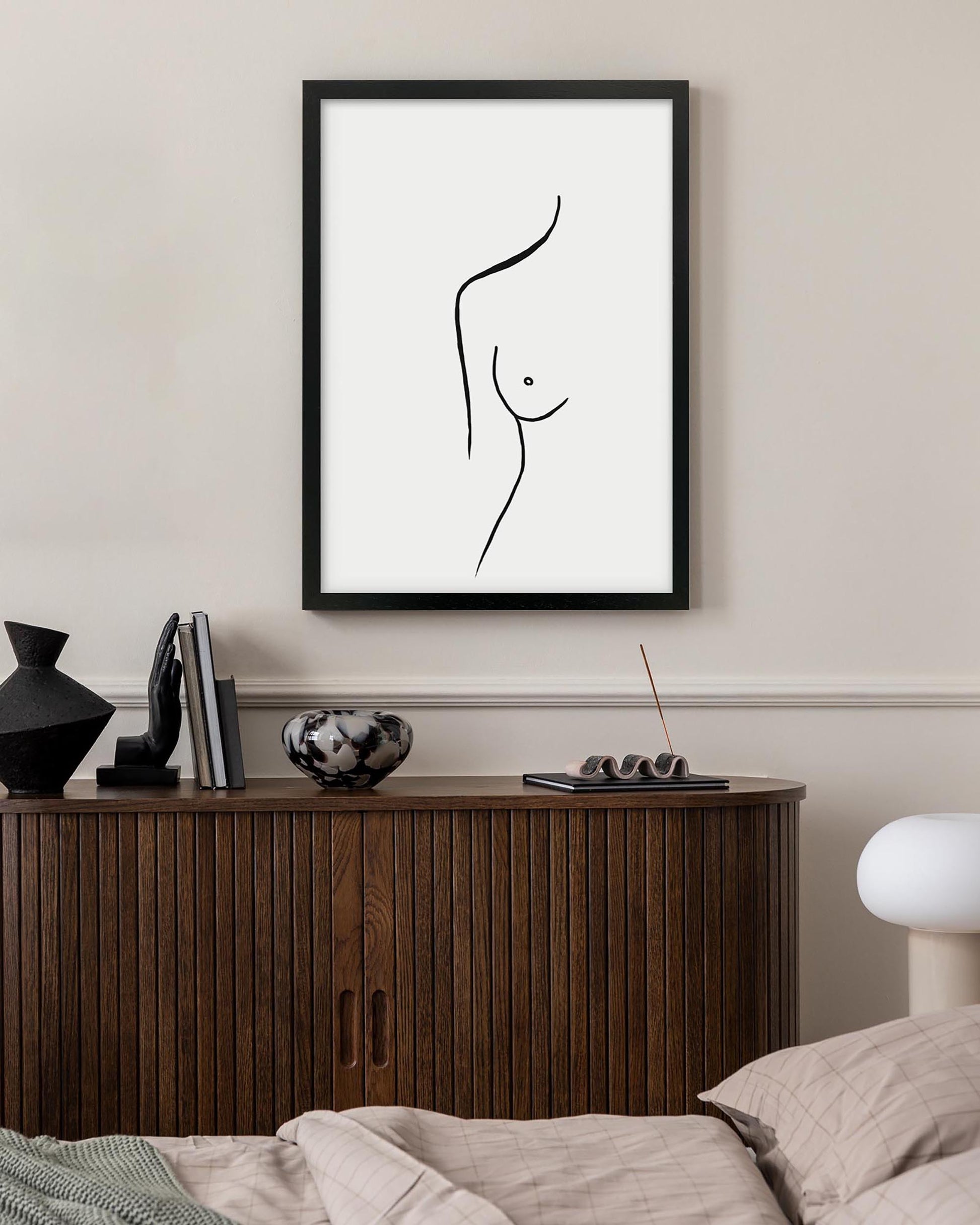Framed black and white abstract art print on a wall above a wooden cabinet.