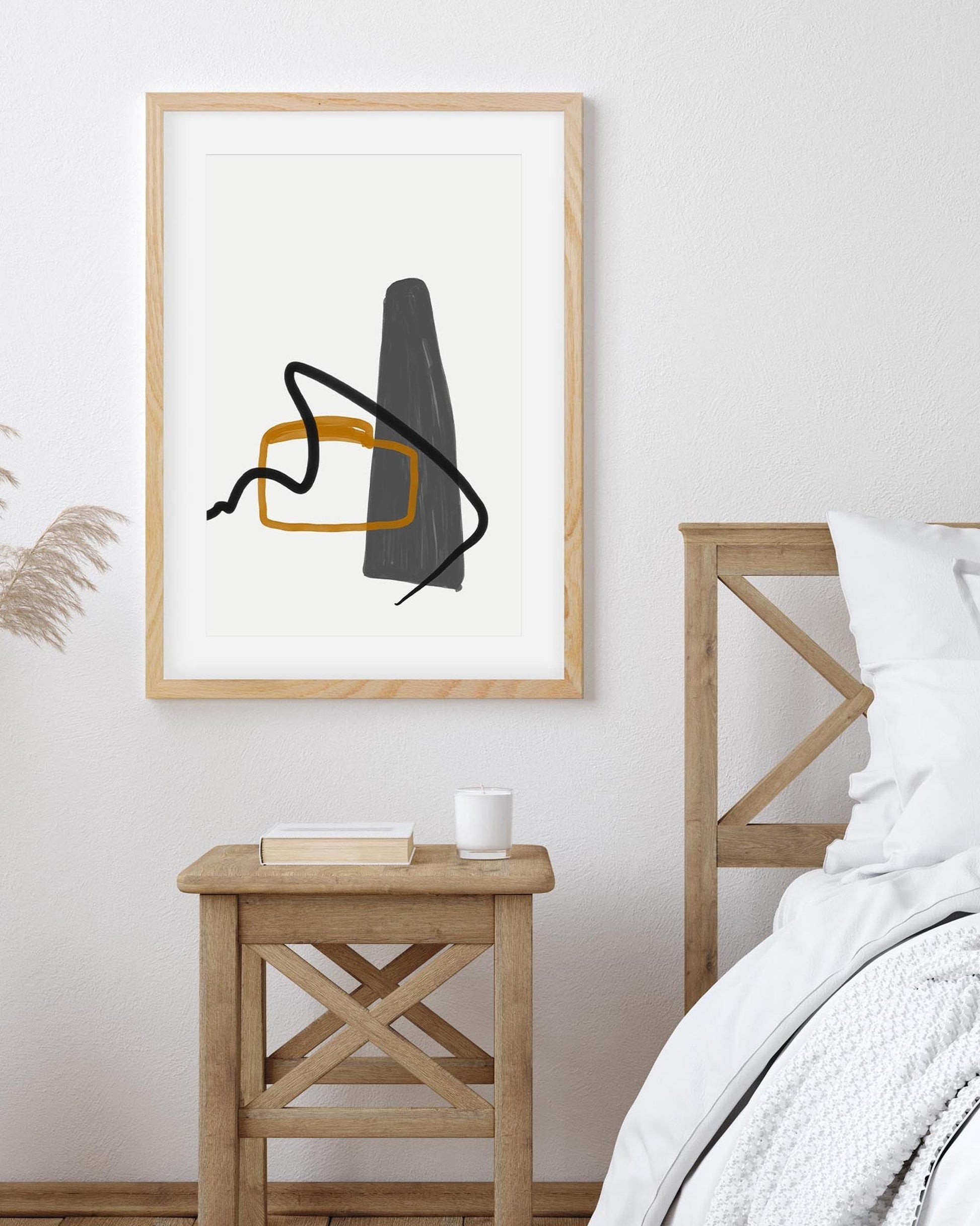 Abstract art print in a wooden frame on a wall above a wooden nightstand.