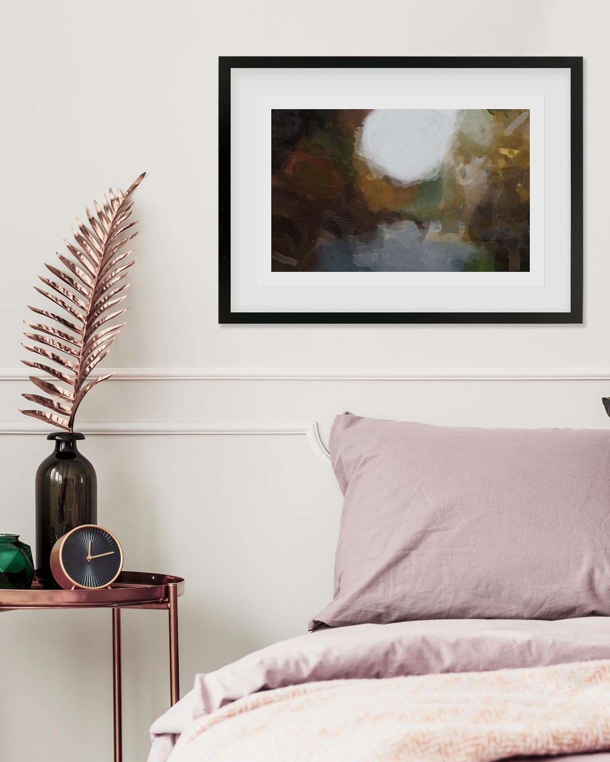 Framed abstract art above a bed with pink bedding and decorative items.