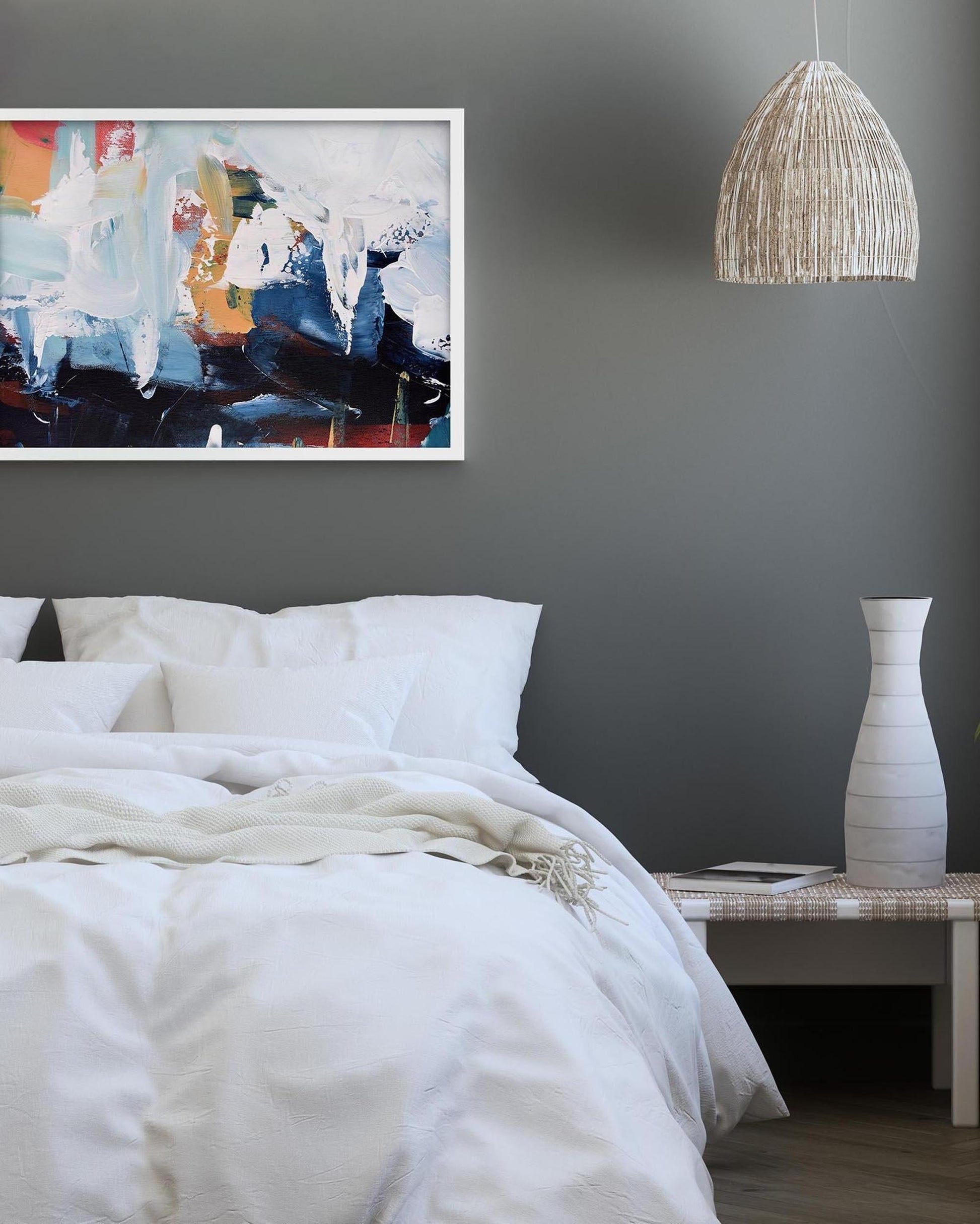 Bedroom with abstract art on the wall, white bedding, and a vase on a nightstand.