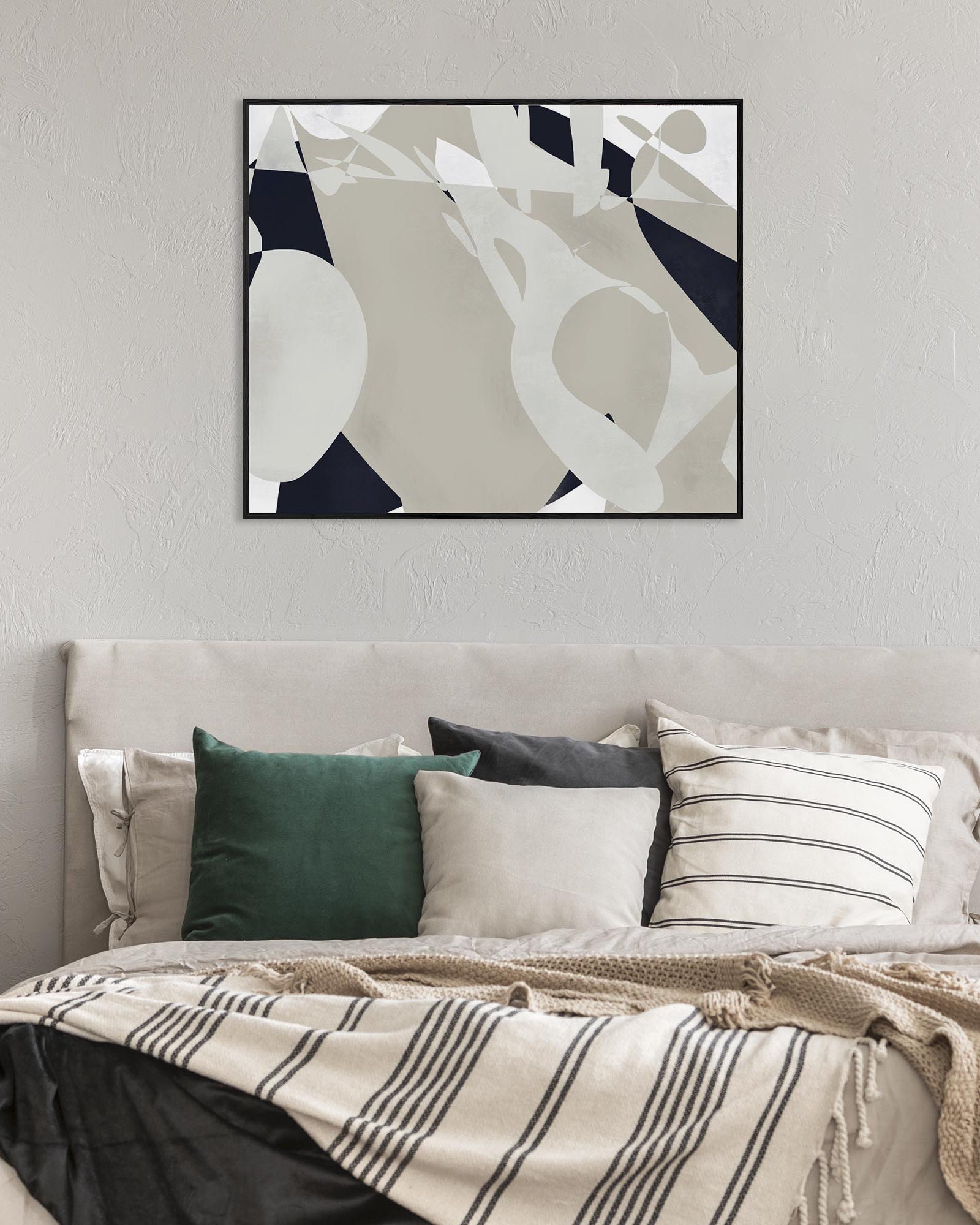 Abstract art print on a wall above a bed with decorative pillows and bedding.