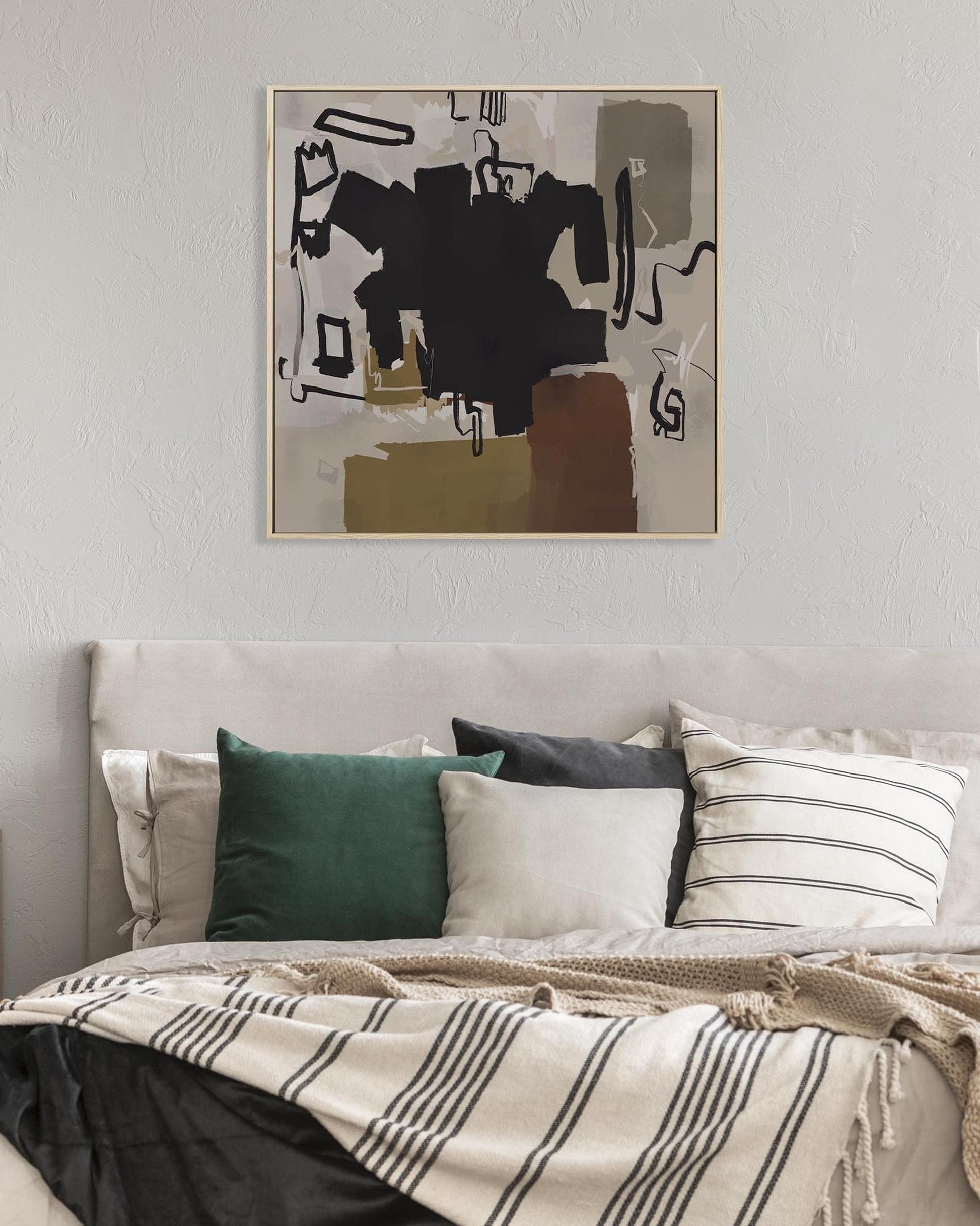 Abstract art above a bed with pillows and blankets
