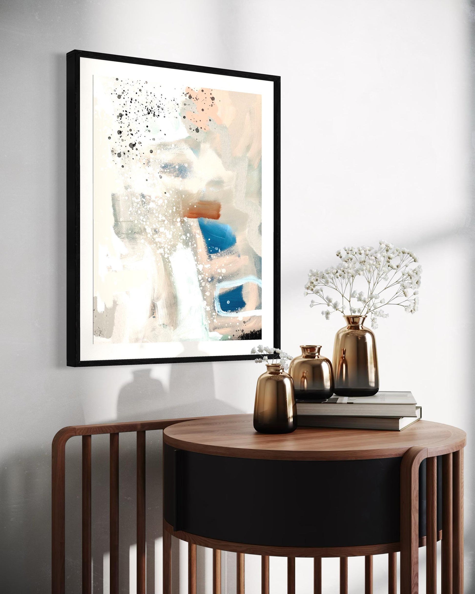 Framed abstract art on a wall above a wooden side table with decorative items.