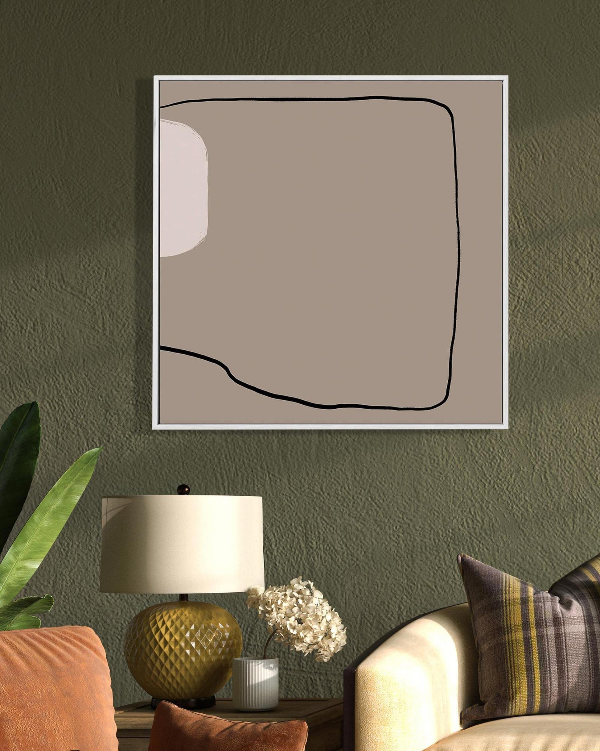 Abstract art piece on a wall with a lamp and plant in the foreground