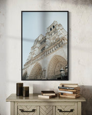Framed photograph of a cathedral on a wall above a wooden side table with books.