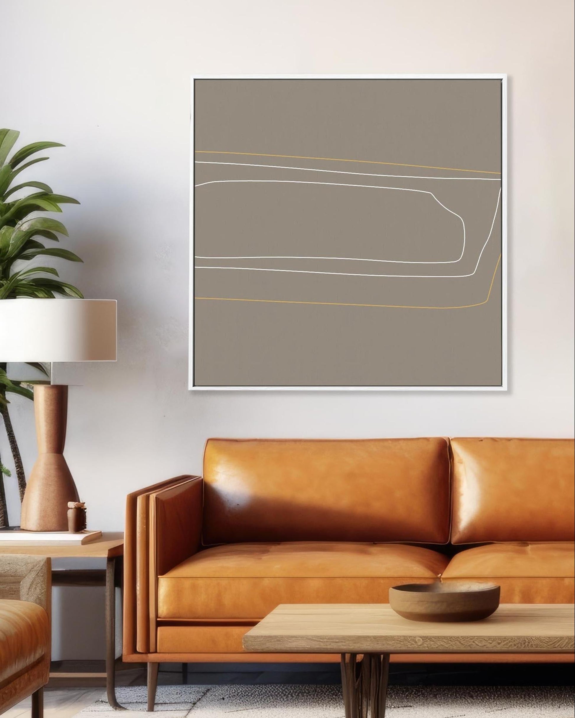 Modern living room with brown leather sofa, abstract art, and potted plant.