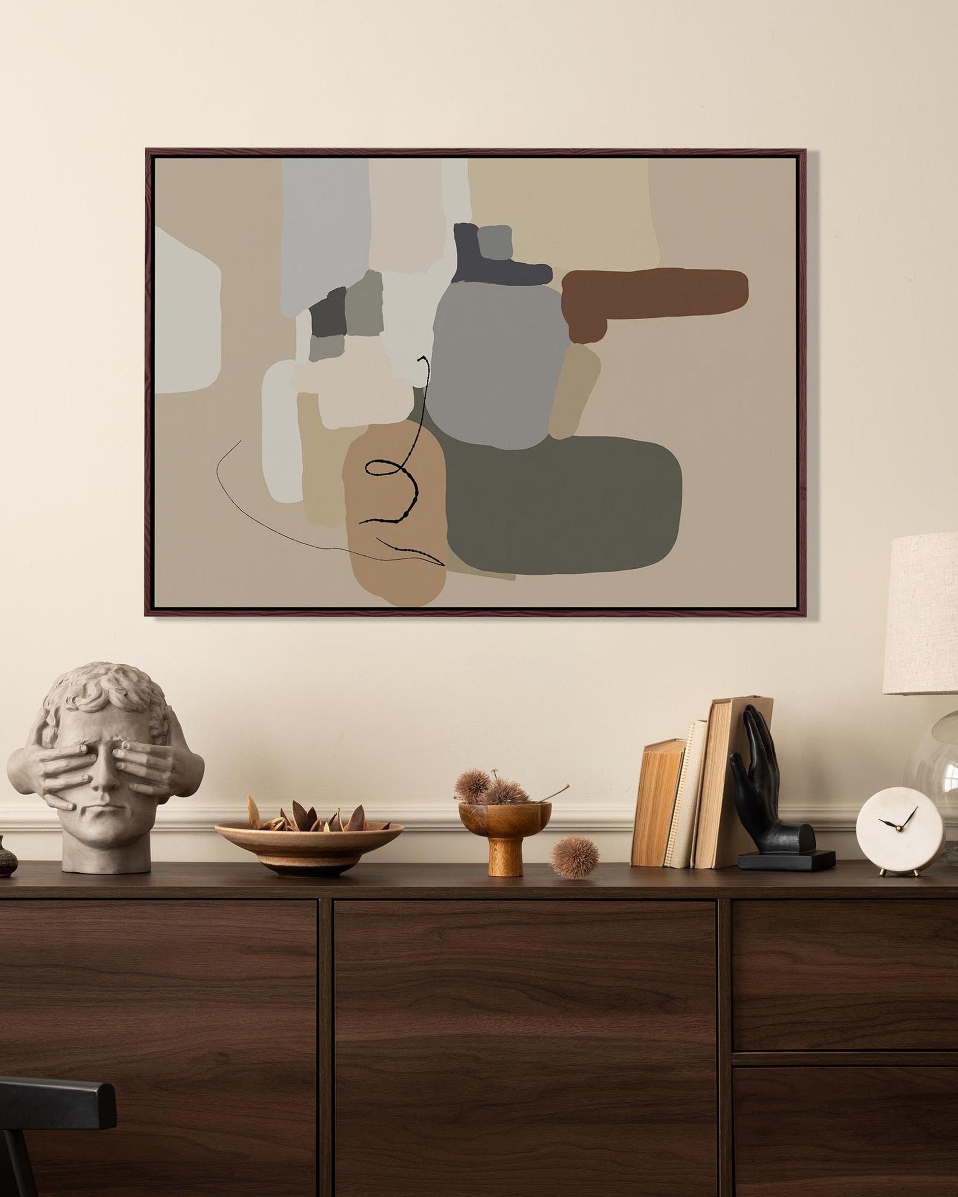 Abstract art piece on a wall above a wooden console table with decorative items.