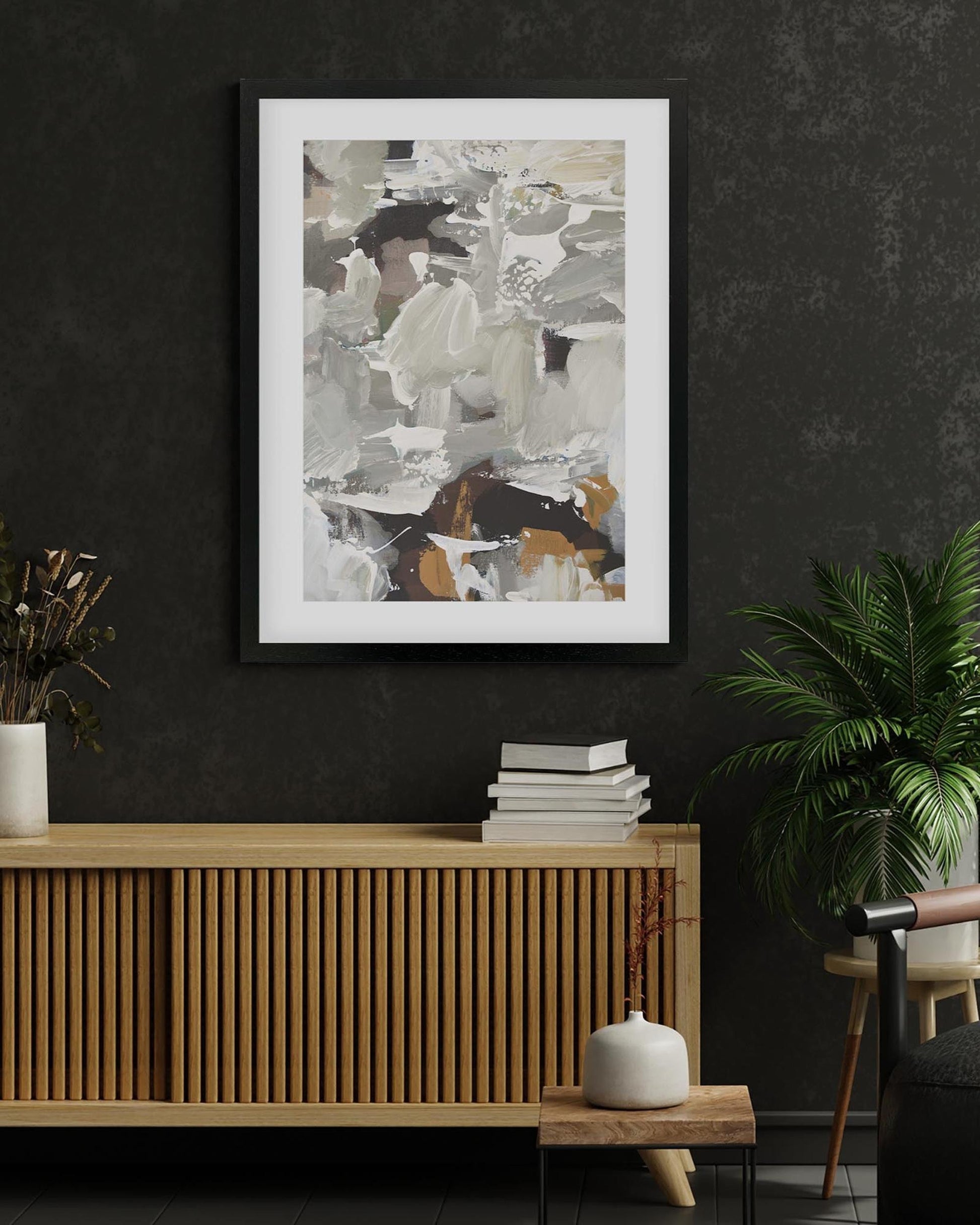 Abstract art print on a dark wall above a wooden console table with books and decor.