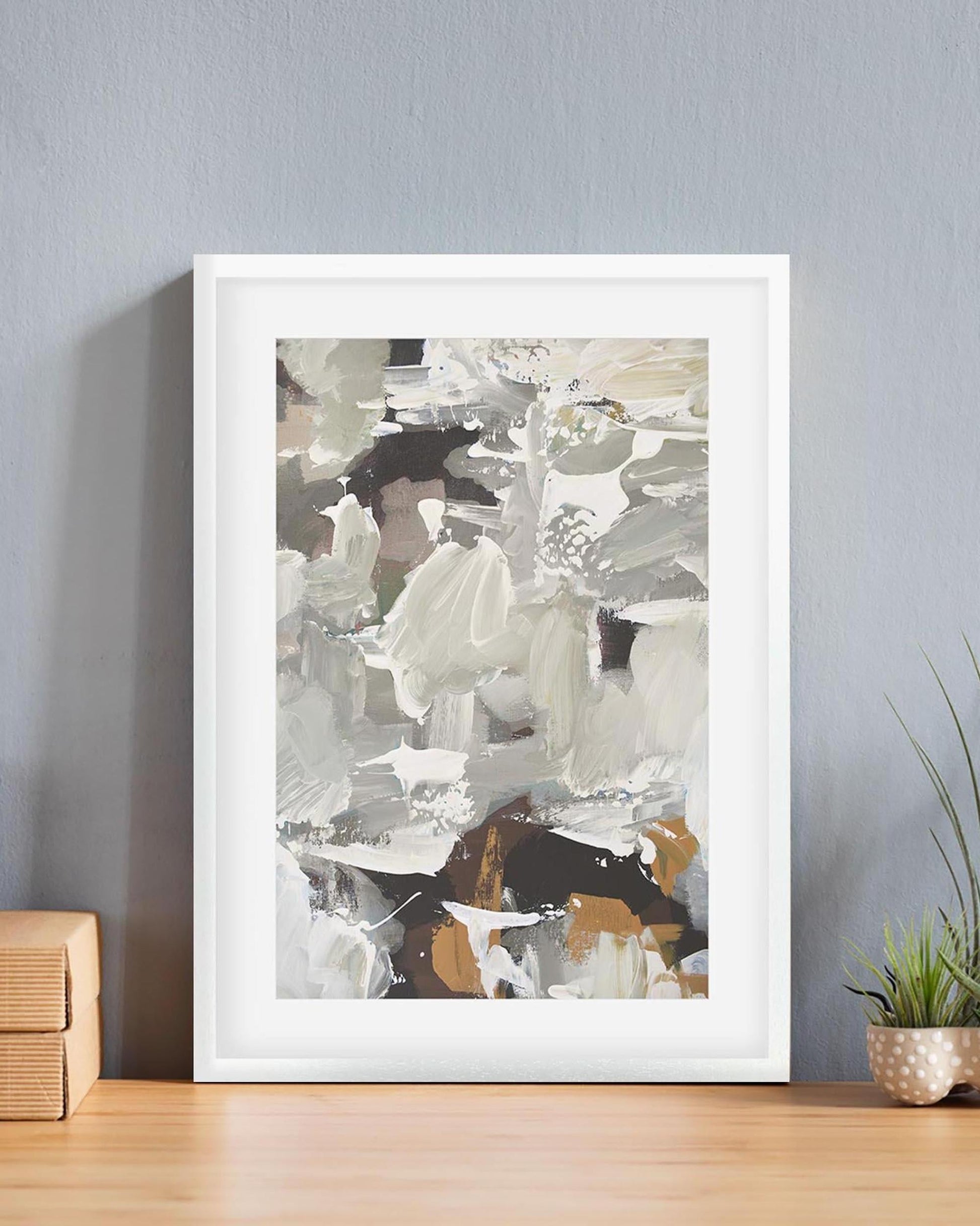 Framed abstract art print on a wall with a plant and wooden box in the background