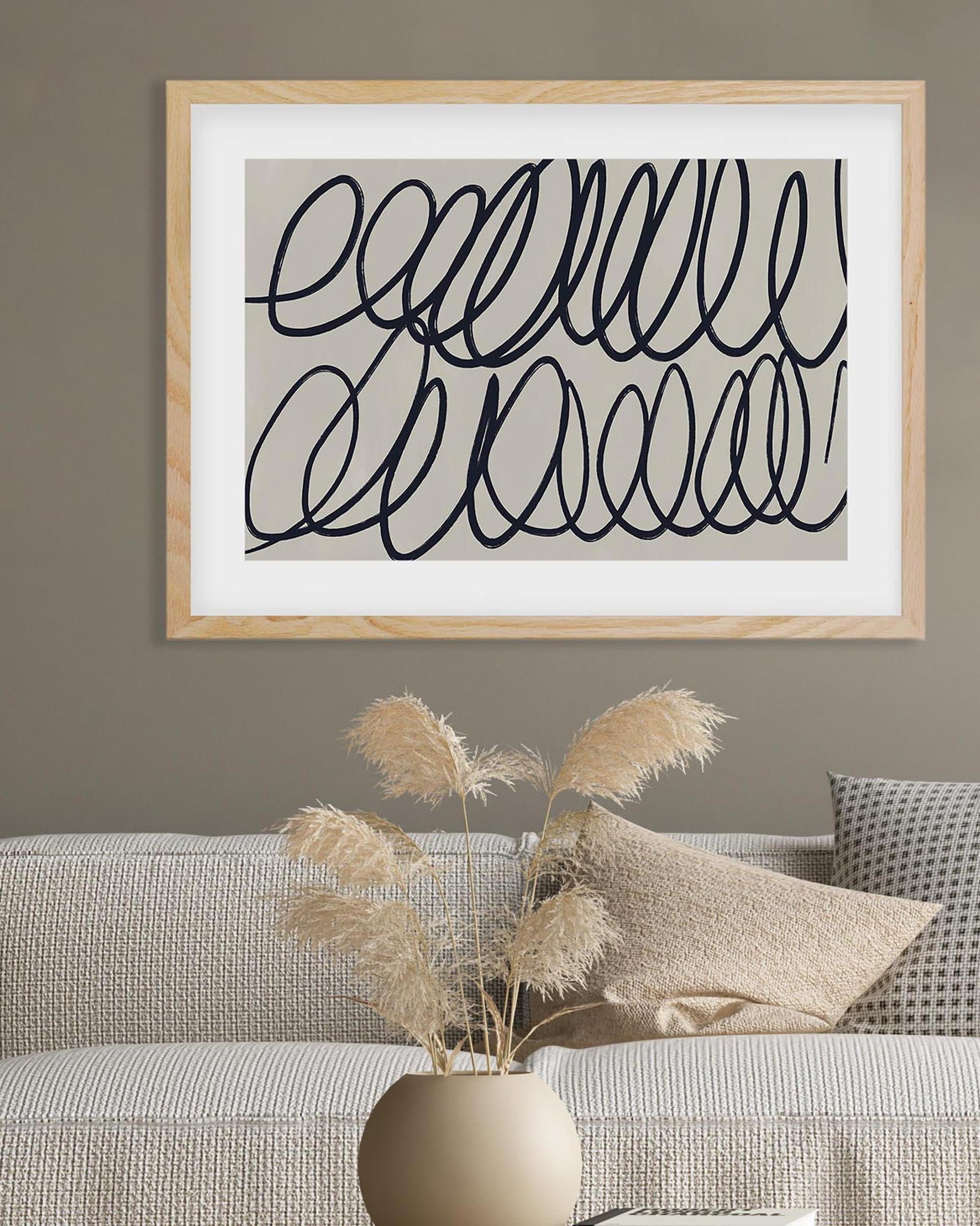 Framed abstract art piece on a wall above a sofa with decorative elements.