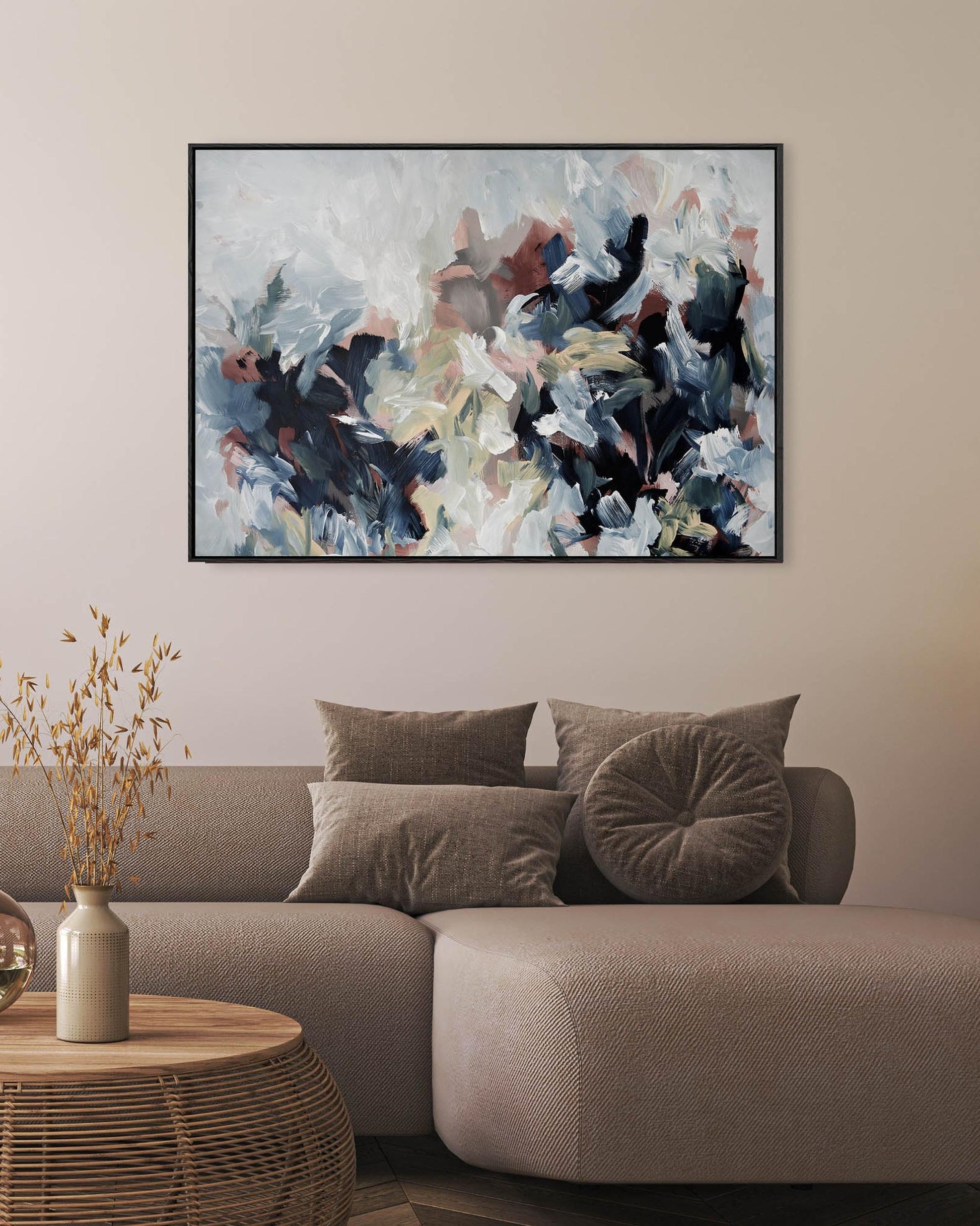 abstract painting on canvas in modern stylish living room with brown sofa, vase and flowers on rattan sustainable coffee table.