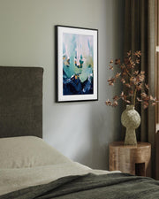 Framed abstract art on a wall above a bed with a vase of flowers on a nightstand.