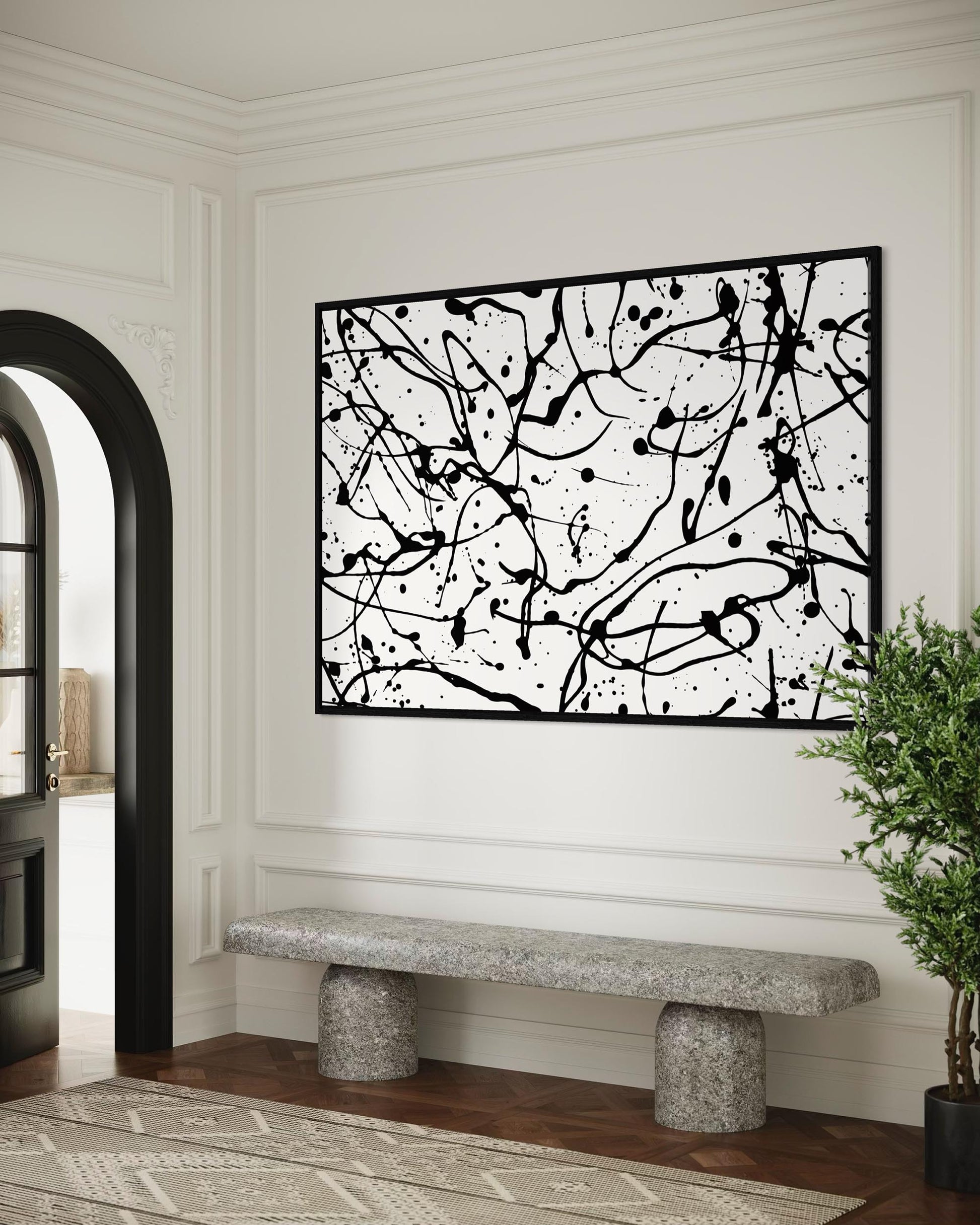 Abstract black and white wall art in a modern interior setting with a stone bench and plant.