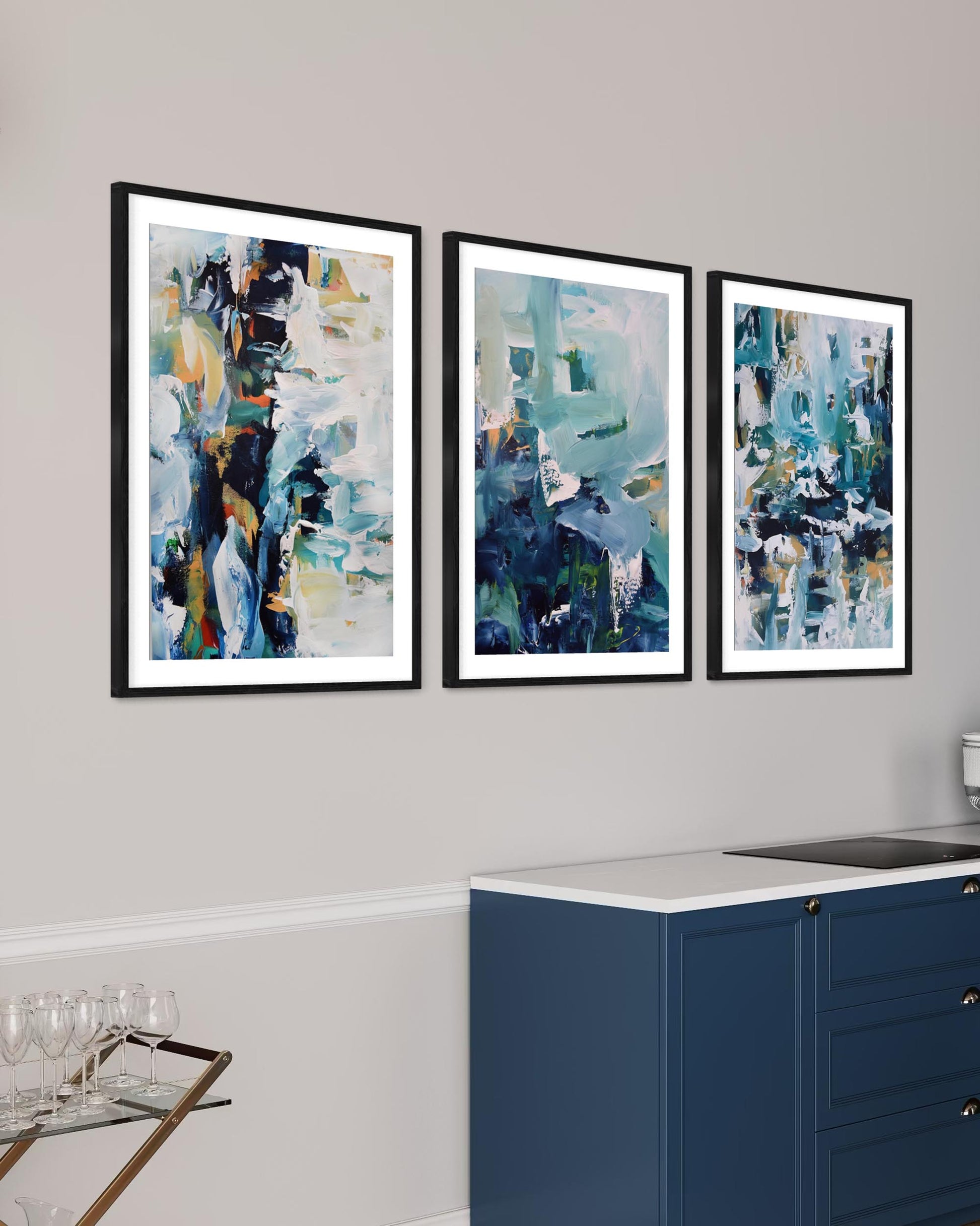 Three abstract art prints on a wall above a kitchen counter.