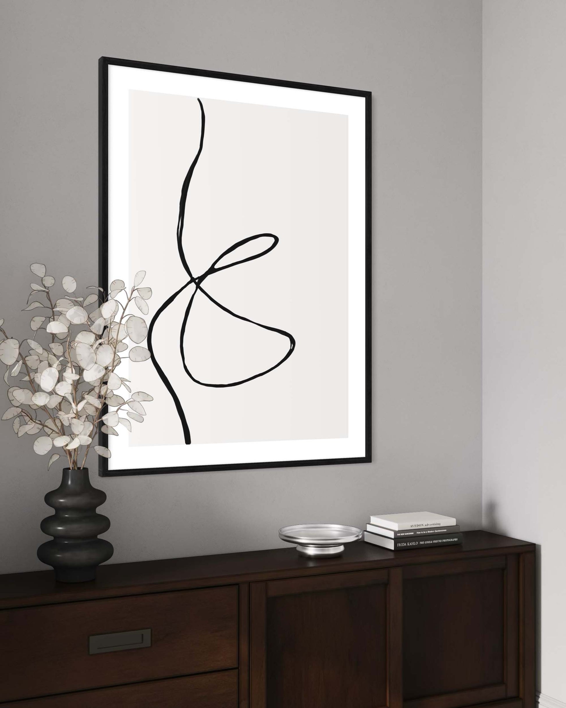 Abstract line art in a black frame on a gray wall above a wooden console table.