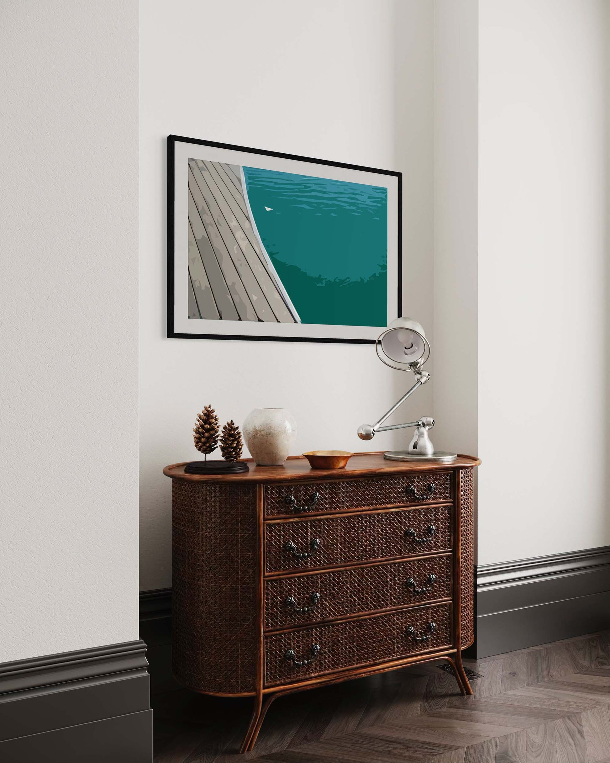Wooden dresser with decorative items against a white wall with a framed picture of a dock.