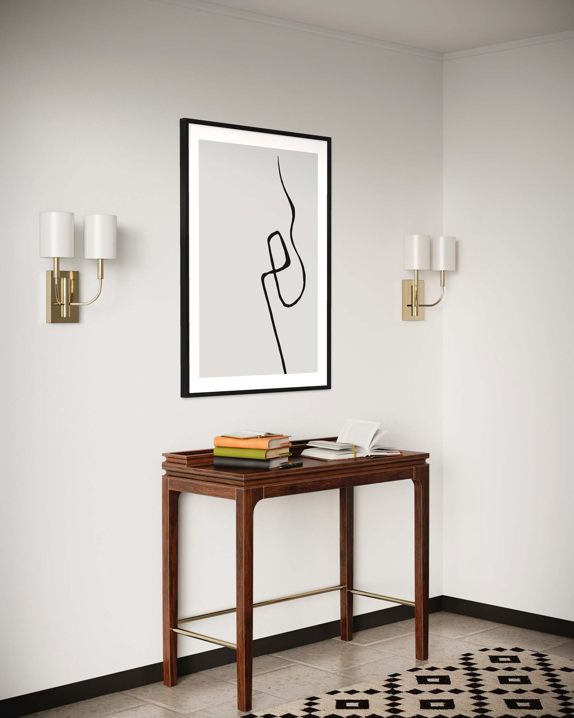 Modern interior with a wooden console table, framed abstract art, and wall sconces.