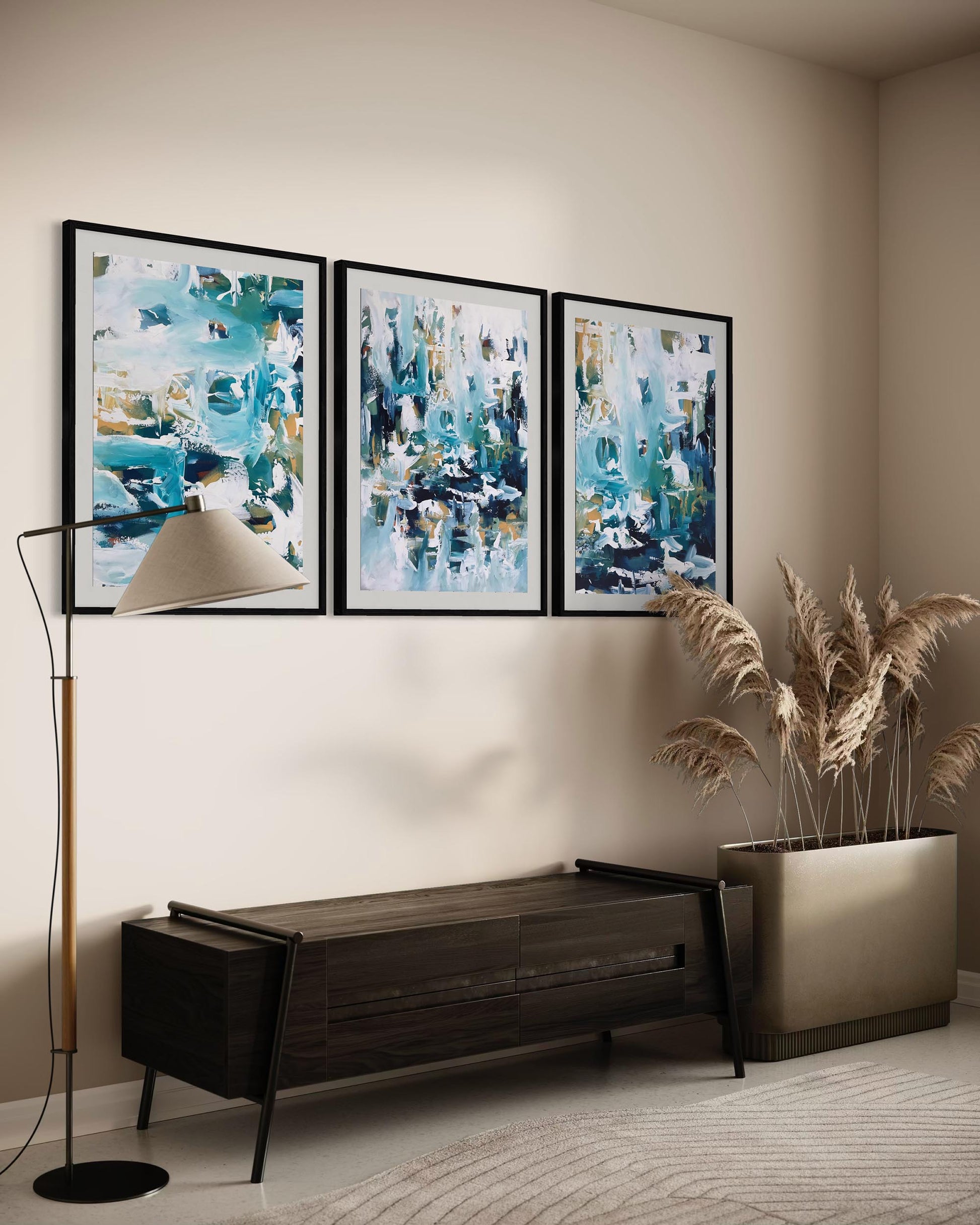 Three abstract paintings on a wall with a bench and decorative plant below.