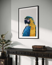 Framed artwork of a colorful parrot on a wall above a wooden table.