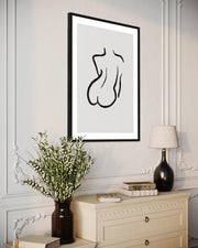 Framed abstract art piece on a wall above a dresser with decorative items.