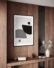 Abstract black and white artwork on a wooden wall with decorative items below.