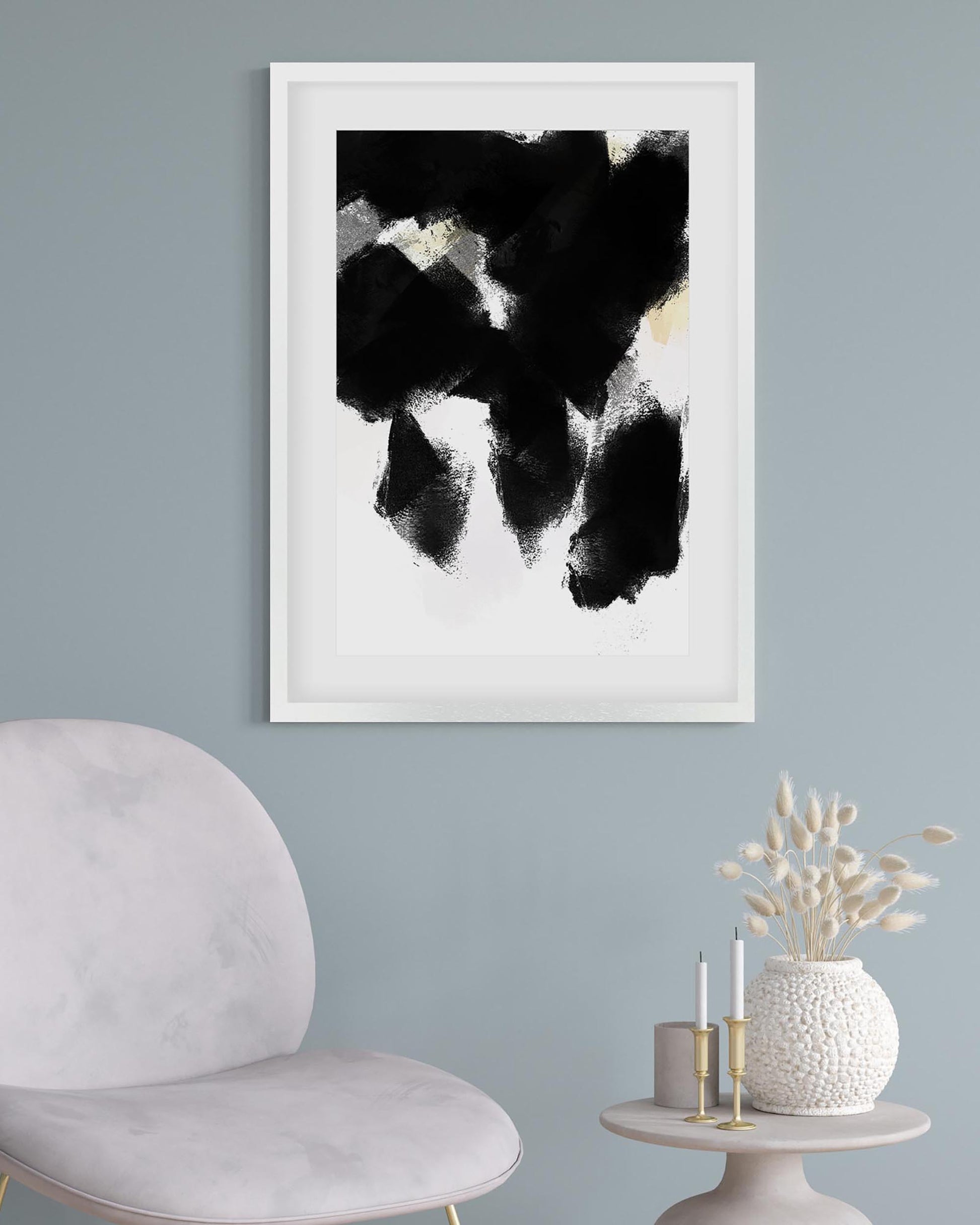 Framed abstract art piece on a wall with a chair and decorative items below.