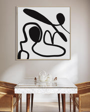 Abstract black and white artwork on a wall above a dining table with chairs.