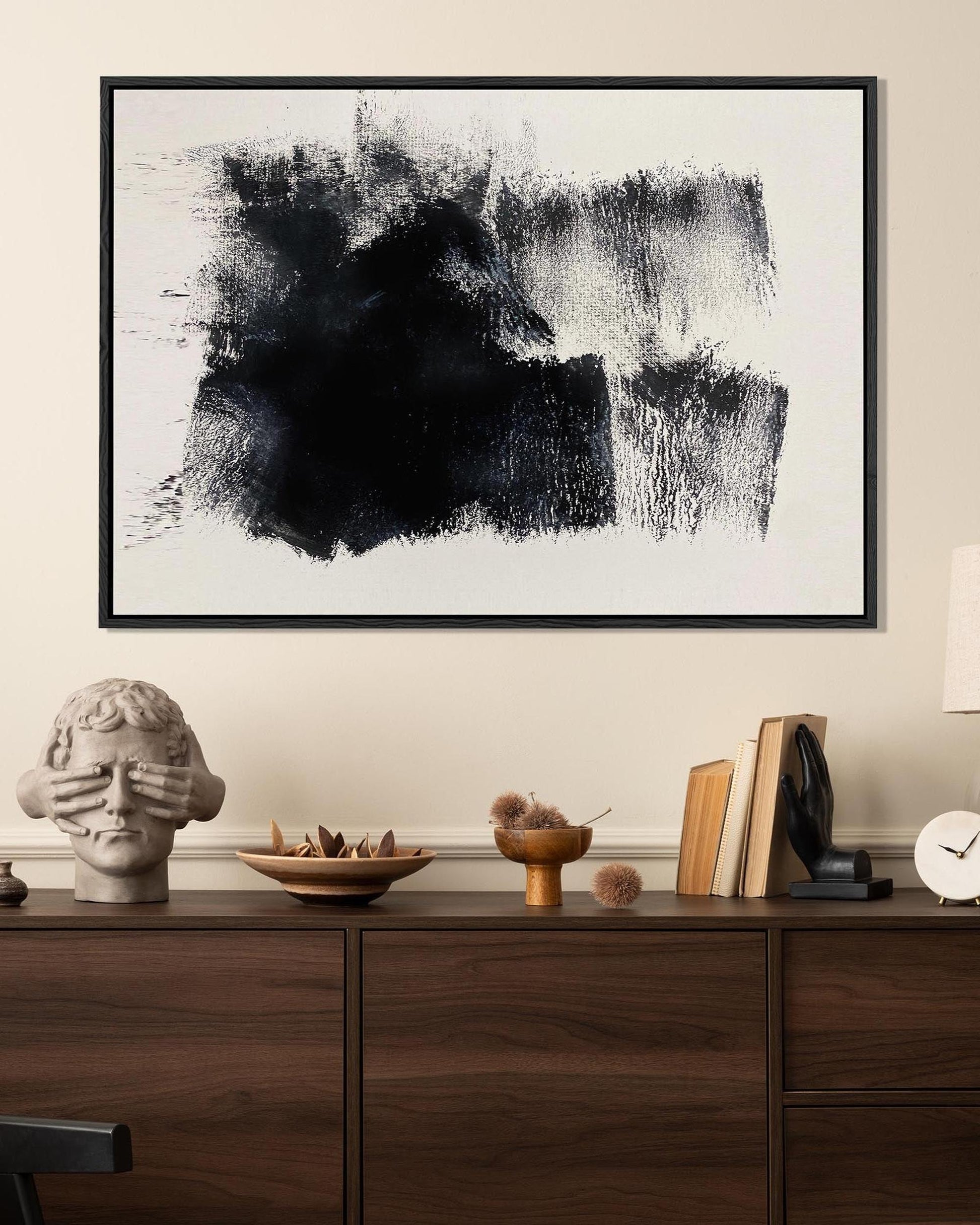 Abstract black and white painting on a wall above a wooden console table with decorative items.